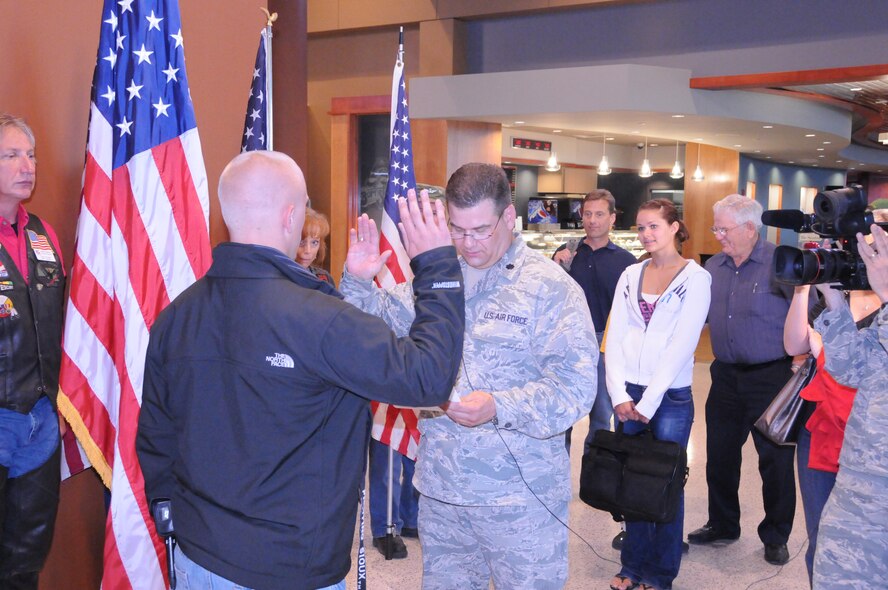 Lt.Col. Dan Bertsch, a staff judge advocate (SJA) with the 119th Wing, North Dakota National Guard, swears in his daughter's boyfriend, Brian Smelden into the North Dakota Air National Guard at Hector International Airport in Fargo on June 11.  The swearing in took place shortly after he returned from a year-long deployment in Afghanistan, prior to that he served in Iraq for seven months.  In the last two years, Bertsch has been deployed more than 18 months; this was his 14th voluntary deployment since Sept. 11, 2001.