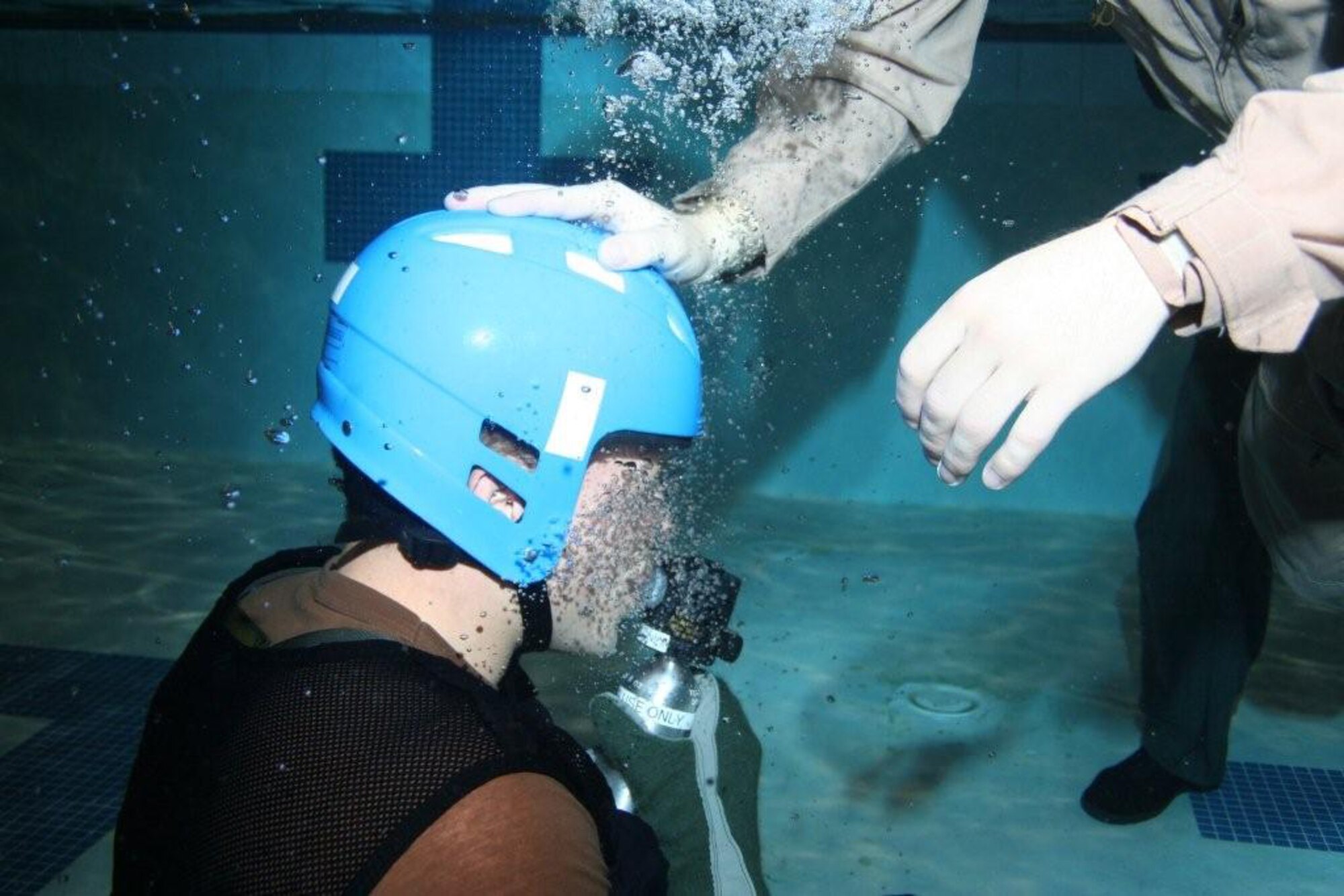 A student is helped underwater as he becomes familiar with a helicopter emergency escape device. (Courtesy photo)