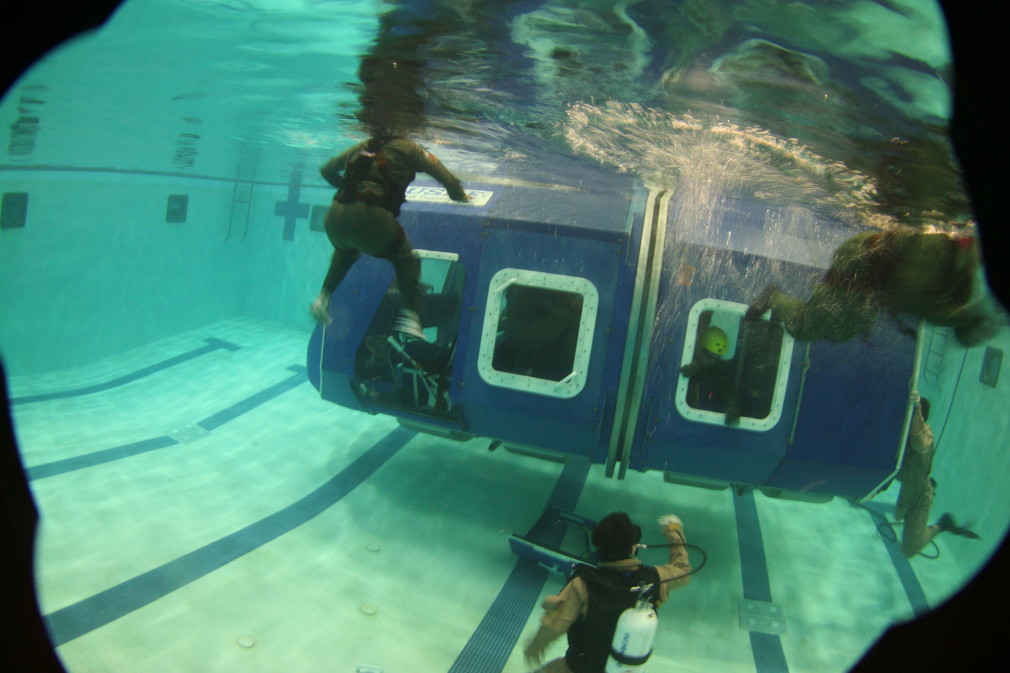 Water survival course students escape from a simulated downed aircraft in a pool at Fairchild. The instructors monitor the exercise, ensuring the students get the required training they need, while staying safe. Students must pass through the water survival course before filling an aircrew position. Seven instructors are onhand to ensure students are safe at all times. The 22nd TRS trains more than 60,000 Airmen a year.  (U.S. Air Force photo/ Staff Sgt. Chad Watkins)