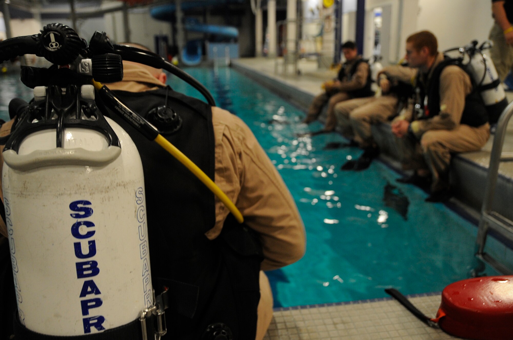 Instructors wait at the edge of the pool for an underwater survival training simulation to begin. The 10 instructors of the 22nd TRS are also qualified on diving equipment. (U.S. Air Force photo/ Staff Sgt. Chad Watkins)