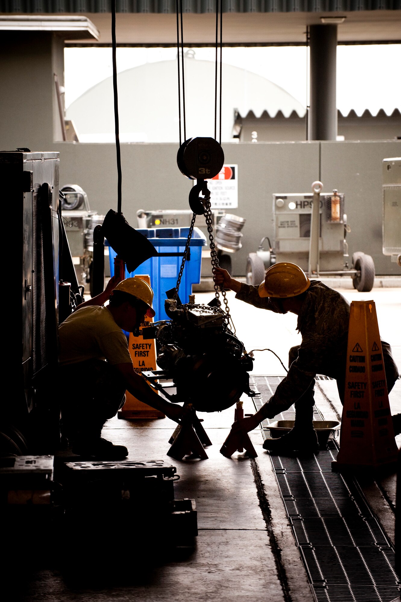 MISAWA AIR BASE, Japan -- Airman 1st Class Devan Copeland and Senior Airman Ryan White, aerospace ground equipment journeymen, 35th Maintenance Squadron AGE flight, lower a four-cylinder engine onto stands at the AGE flight maintenance shop June 18. (U.S. Air Force photo/Staff Sgt. Samuel Morse)