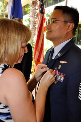 Senior Master Sgt. Richard Ugalde, 624th Aeromedical Staging Squadron Nursing and Aerospace Medicine Superintendent, watches as his wife Barbara places a retirement pin on his lapel at a ceremony held June 12 at the Courtyard of Heroes, Pacific Air Forces, Headquarters, Joint Base Hawaii Pearl Harbor Hickam. Sergeant Ugalde entered the U.S. Air Force in June 1986 as an Electronic Warfare Systems Specialist.  After completing 5 and a half years of active duty service, he joined the Air Force Reserve in November 1991 cross-training as a Medical Service Specialist.