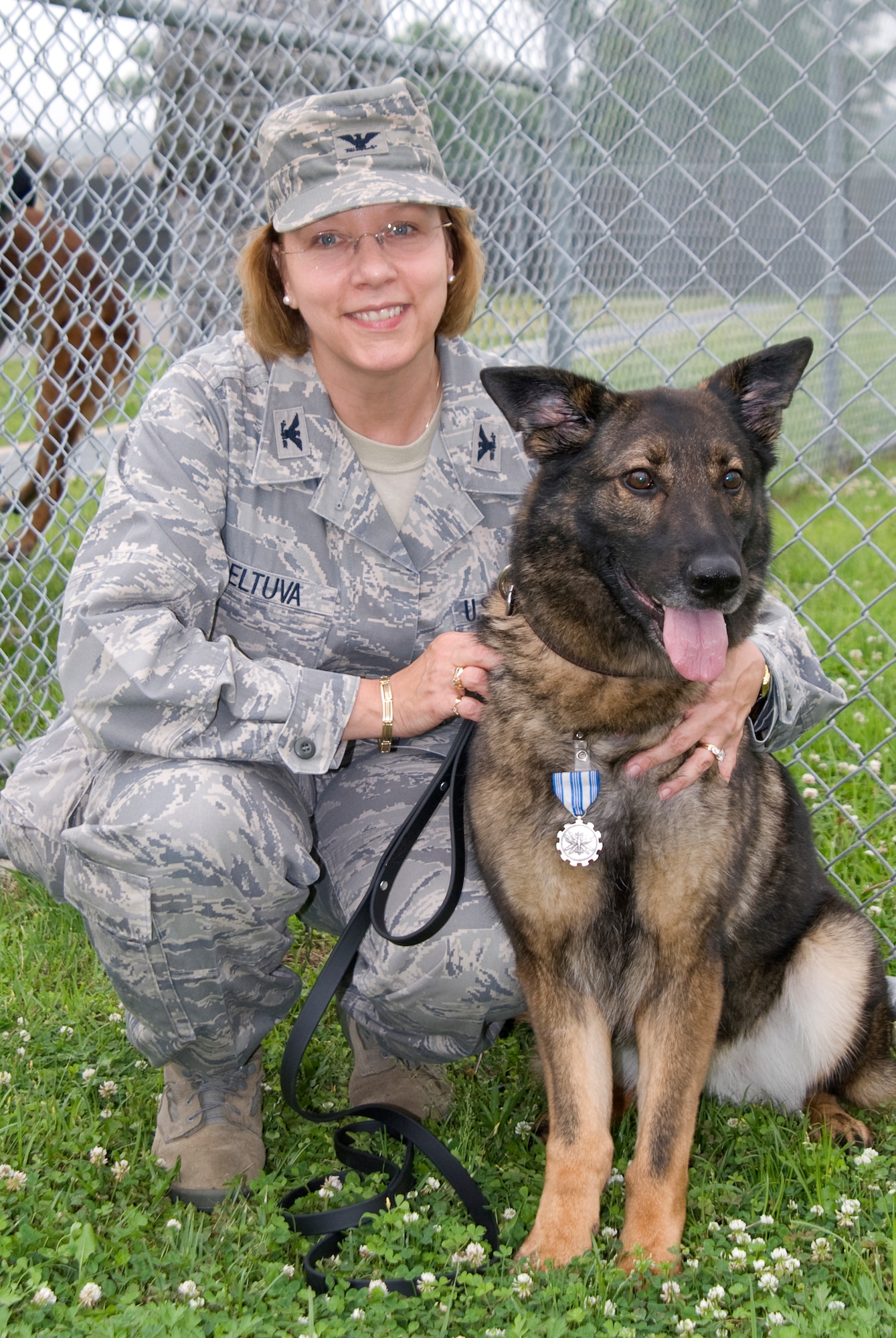 KUNSAN AIR BASE, Republic of Korea -- Col. Janet Deltuva, 8th Medical Group commander, poses with military working dog Emzy after Emzy was officially retired during a ceremony June 17. Emzy is an eight-year-old German Shepherd with five years of service at Kunsan. Colonel Deltuva has adopted her. (U.S. Air Force photo/Staff Sgt. Jonathan Pomeroy)
