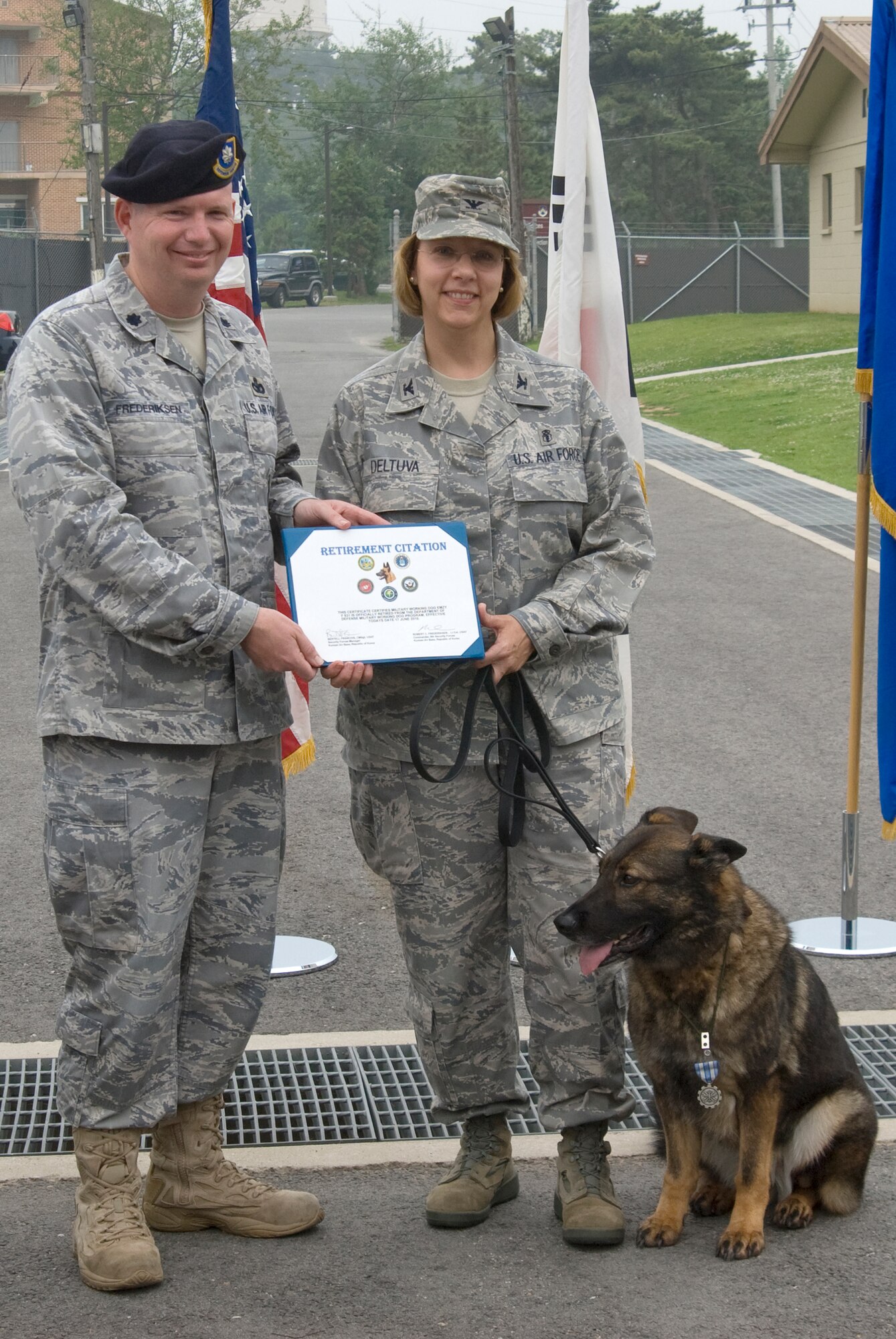 KUNSAN AIR BASE, Republic of Korea -- Col. Janet Deltuva, 8th Medical Group commander, accepts a retirement certificate from Lt. Col. Robert Frederiksen, 8th Security Forces Squadron commander, on behalf of Emzy, a military working dog and eight-year-old German Shepherd with five years of service at Kunsan. Emzy was officially retired during a ceremony June 17. Colonel Deltuva has adopted her. (U.S. Air Force photo/Staff Sgt. Jonathan Pomeroy)