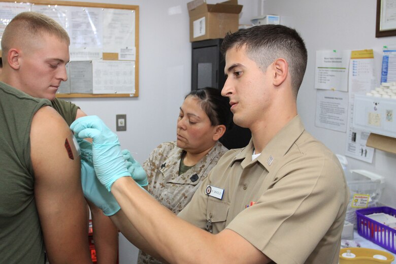 Seaman Richard Grassley, Robert M. Casey Medical and Dental Clinic immunizations work center supervisor, administers small pox immunization shots to Pfc. Edward York II at the Branch Health Clinic here June 18. Grassley is currently in charge of administering shots to all base dependents.