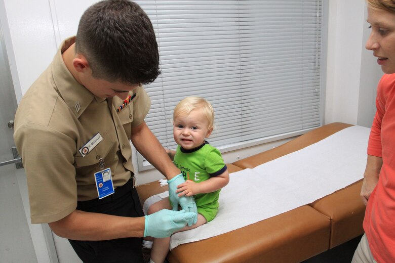 Seaman Richard Grassley, Robert M. Casey Medical and Dental Clinic immunizations work center supervisor, administers a vaccine to 14-month-old Zach Hollowell at the Clinic here June 18.