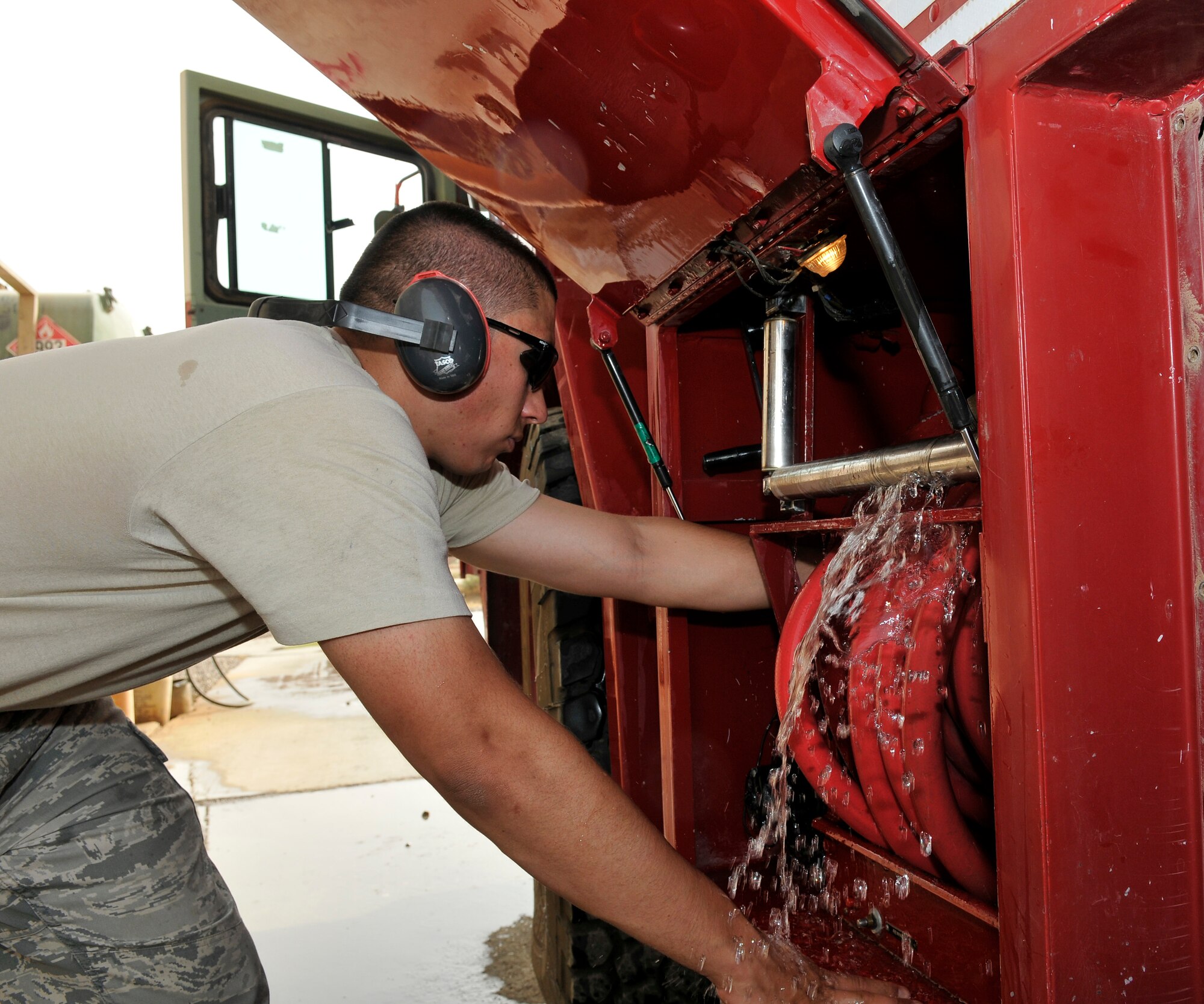 Staff Sgt. James Polk, 332nd Expeditionary Logistics Readiness Squadron Fire Truck Maintenance Shop vehicle maintenance technician, works to shutoff water pouring from a hose storage compartment June 18, 2010, Joint Base Balad, Iraq. The fire truck was brought into maintenance with a severe vibration problem when spraying water. Sergeant Polk is deployed from MacDill Air Force Base, Fla. (U.S. Air Force photo\Staff Sgt. Phillip Butterfield)
