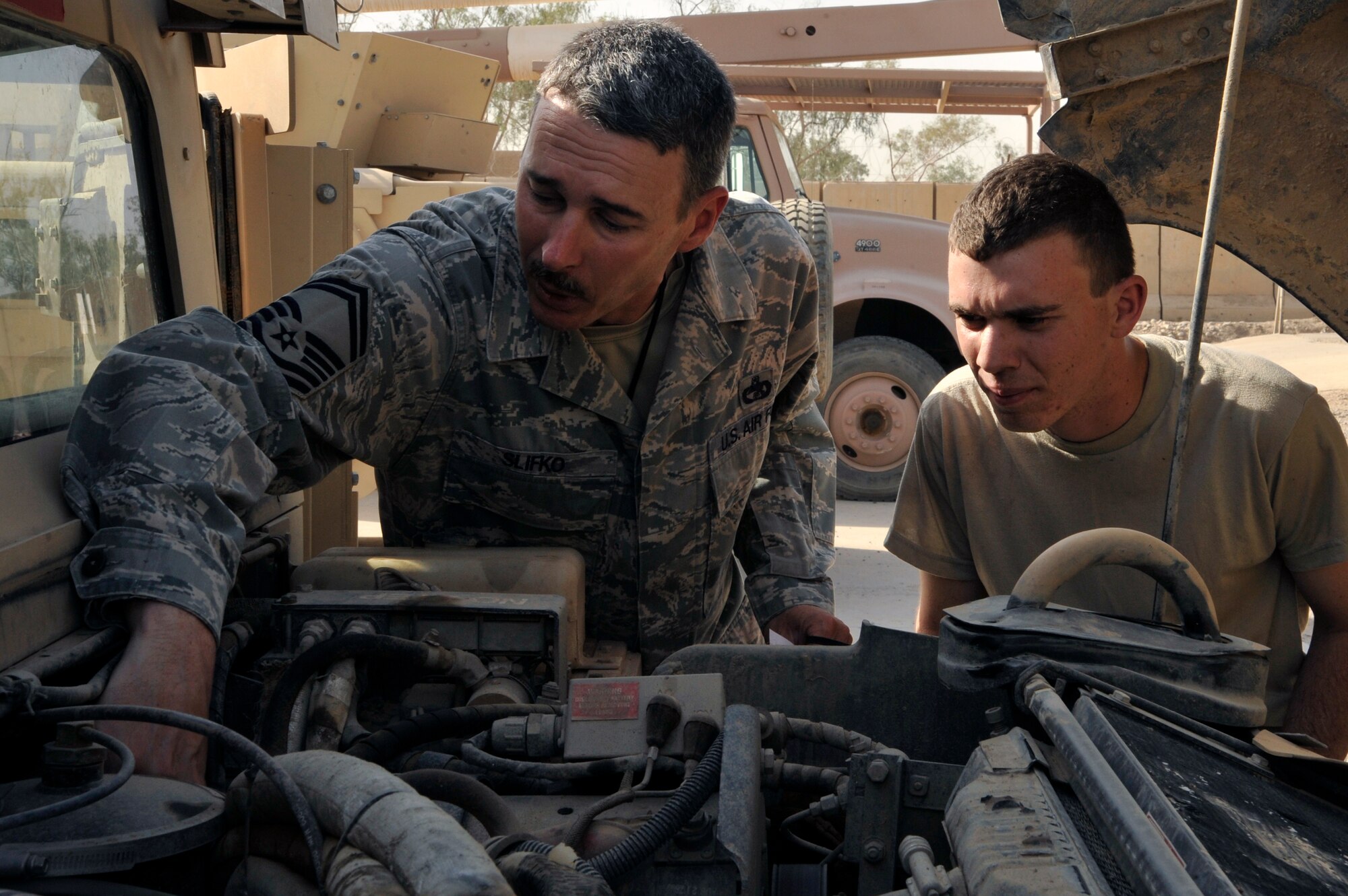 Senior Master Sgt. CJ Slifko, 447th Expeditionary Logistics Readiness Squadron, vehicle fleet manager, deployed from McConnell Air Force Base, Kan., points out a fuel leak to his son, Airman 1st Class Ryan Slifko, 447th ELRS, vehicle mechanic, deployed from Whiteman AFB, Mo. They performed a limited technical inspection on an excess Humvee to determine if it's in a good enough condition to be sent to Afghanistan or sent to a depot to be rebuilt, June 19, 2010, at Sather Air Base, Iraq. Airman Slifko, from Derby, Kan,, joined the Air Force and went into the same career field, and deployed to the same unit as his father. (U.S. Air Force photo by Senior Airman Perry Aston/Released)