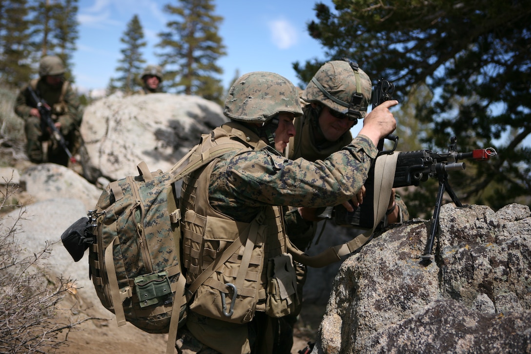A fire team of Marines with 1st Battalion, 25th Marine Regiment, load ammunition into a squad automatic weapon and prepare to assault a mock enemy force.