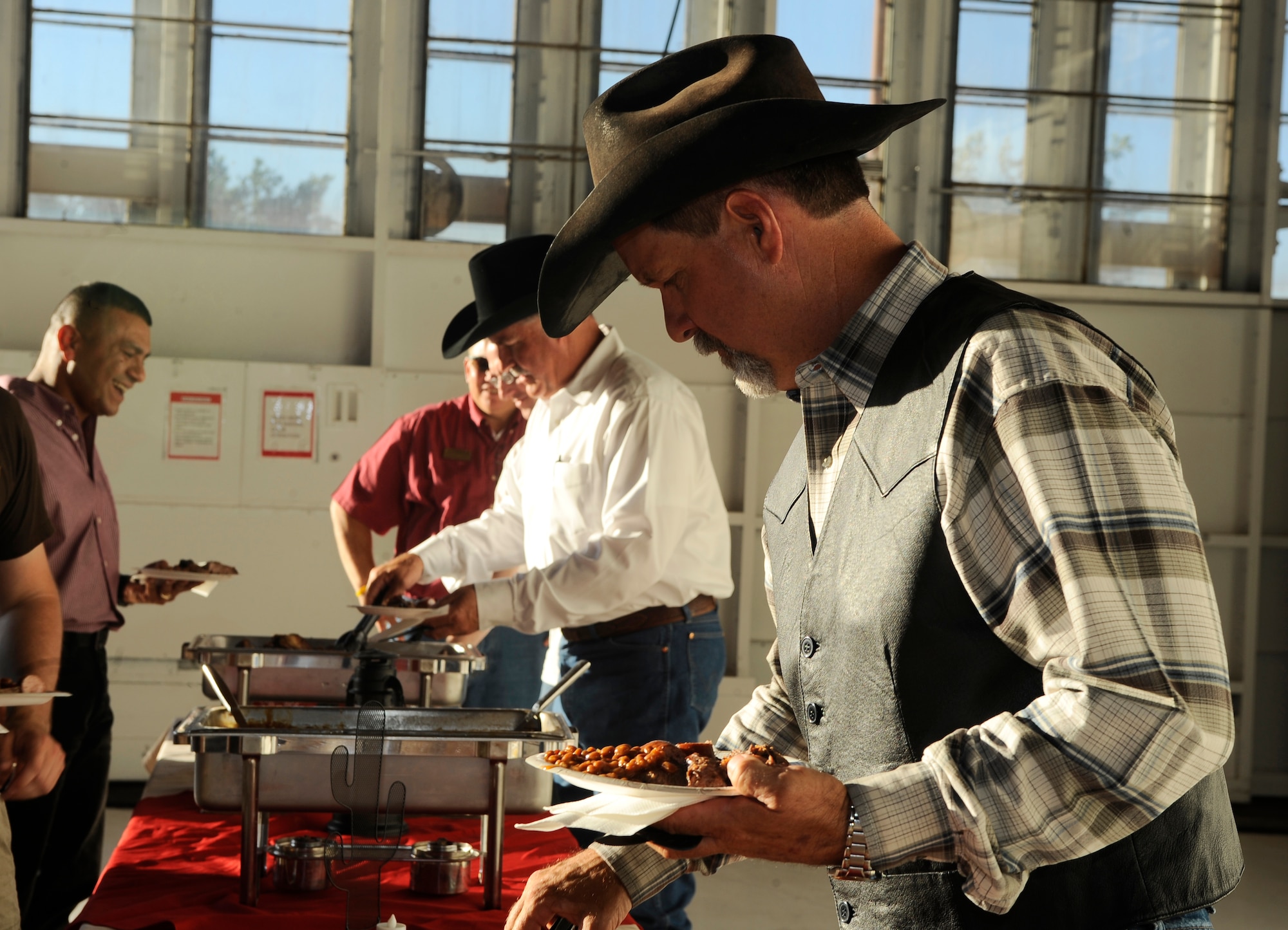 HOLLOMAN AIR FORCE BASE, N.M. -- Members of Holloman fill their plates with hot beans, cornbread and barbeque meat at the "Cowboy Cook-Out" farewell dinner held for Col. Jeff Harrigian, 49th Fighter Wing commander, June 18, 2010. Members of Team Holloman attended the party at Hangar 877 for a night of live country music, food and to give a final goodbye to Colonel Harrigian and his family. (U.S. Air Force photo by Senior Airman Veronica Stamps / Released)