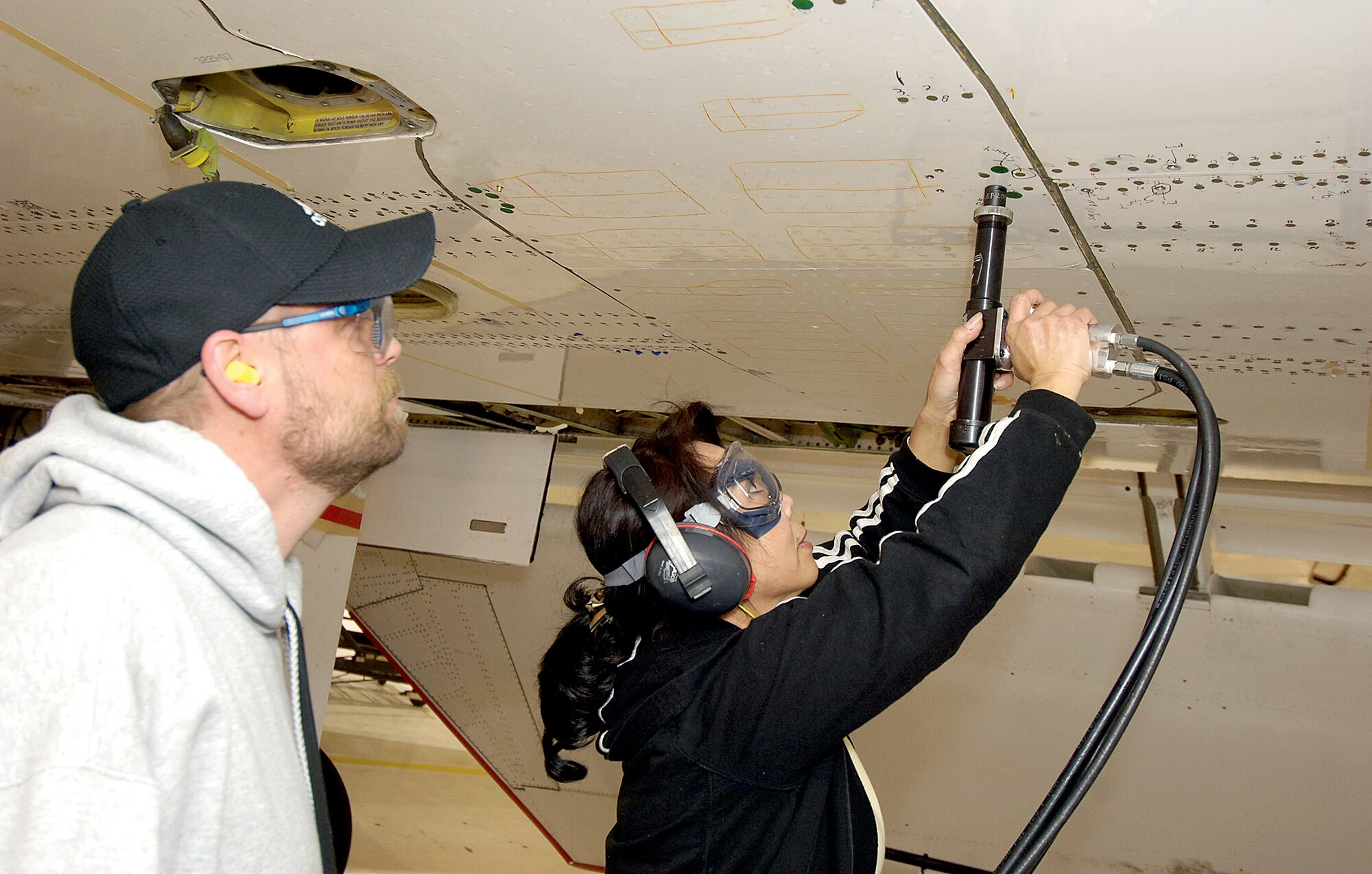 Eric Dart and Kimberly Nguyen strengthen the wings on a Navy E-6 so it will better endure stress from the angle the jet assumes during missions June 11, 2010 at Tinker Air Force Base, Okla. Dart and Nguyen are sheet metal mechanics in the 566th Aircraft Maintenance Squadron. (U.S. Air Force photo/Margo Wright)