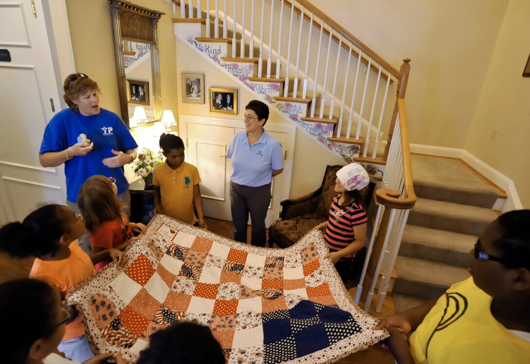 JOINT BASE ANDREWS, Md. -- Debbie Carle, left, Andrews Youth Center representative, and the Andrews School Age Program Quilting Club participants present a quilt they began in January to Melanie Dennison, center, Fisher House representative, June 11. The Quilting Club members created the quilt as a community project and wanted to present the quilt to the Fisher House since one of the youth was a one-time resident. (U.S. Air Force photo by Bobby Jones)