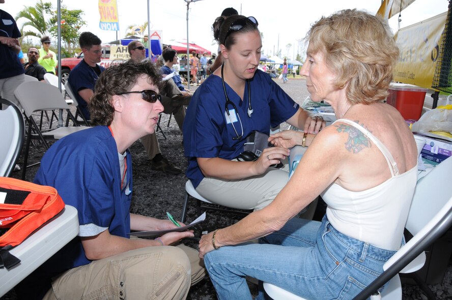 While Maj. Ruthann Murphy, a registered nurse talks to a patient, Staff Sgt. Katie Duff, a medical technician checks the patient's pulse. Murphy and Duff are with the 193rd Special Operations Wing's Medical Group out of Middletown, Pa. The 193rd Medical Group provided free health screenings at Maku'u Farmer's Market in Pahoa, Hawaii, on June 13th, 2010. Members of the 193rd Medical Group are in Hilo, Hawaii, for Medical Innovative Readiness Training.