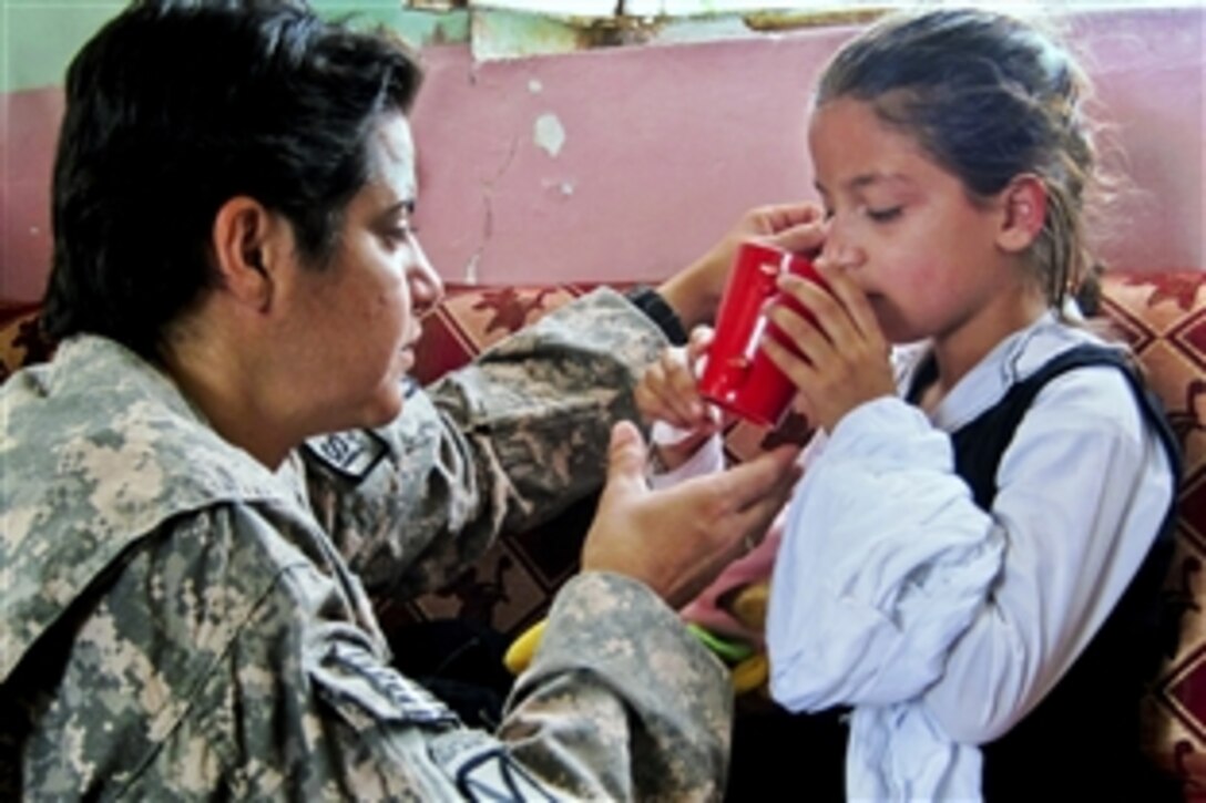 U.S. Army Sgt. Milda Hawkins helps an Afghan girl drink water after she passed out from dehydration in Heyratan, Afghanistan, June 14, 2010. Hawkins, a medical specialist assigned to the 10th Mountain Division’s 1st Brigade Special Troops Battalion, was visiting the Nasir Girl’s School in Heyratan to assess its educational and medical needs.