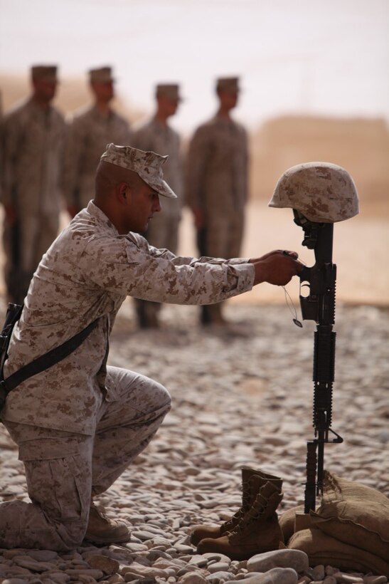 A member of the memorial cross detail places Cpl. Jeffrey Standfest’s dog tags around the pistol grip of a M16 A2 service rifle during a memorial service held to honor Standfest June 22. Deployed to Afghanistan with Company A, 3rd Combat Engineer Battalion, Regimental Combat Team 2, Standfest was killed by an improvised explosive device while attempting to clear a building of suspected IEDs.