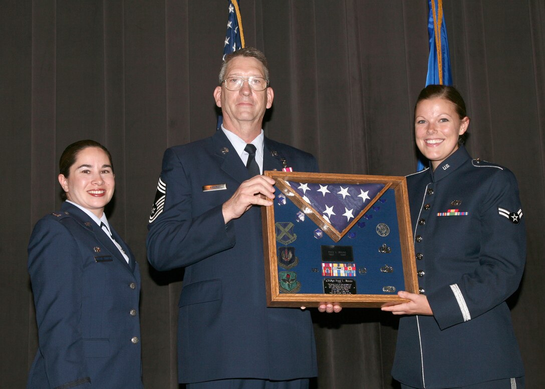 Captain Cristina Moore Urrutia, Chief Fred Brunz and Airman First Class Laura Hall pose for a picture after A1C Hall presented Chief Brunz with a shadowbox in honor of his retirement.