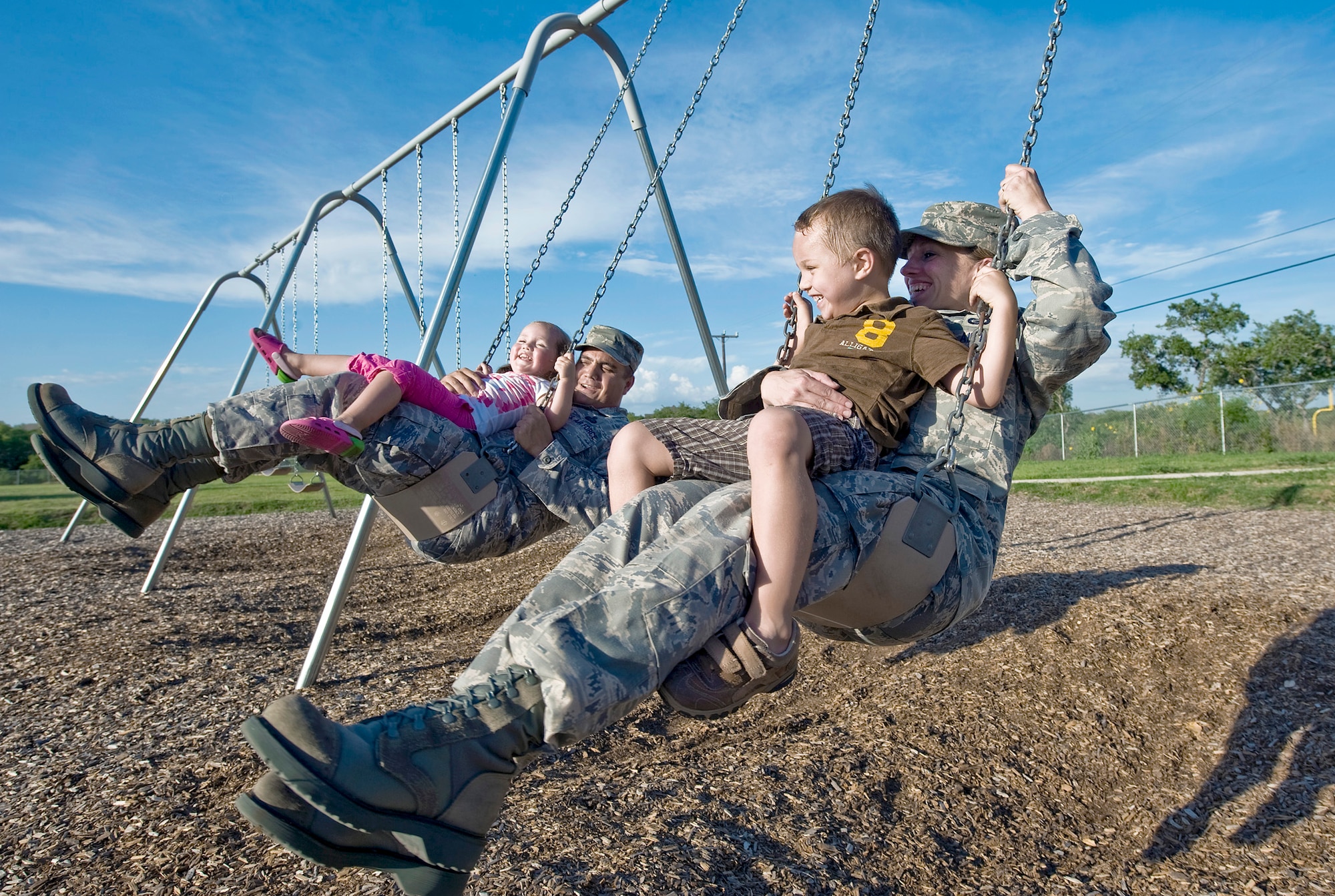 Master Sgt. Roldolfo Gamez and his wife, Tech. Sgt. Christina Gamez, swing with their children at their neighborhood park after work. (U.S. Air Force photo/Staff Sgt. Bennie J. Davis III)