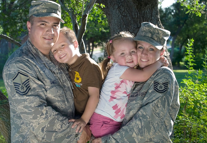 Master Sgt. Rodolfo Gamez and his wife, Tech. Sgt. Christina Gamez, hold their children, Tomas, 4, and Eva, 3, for a portrait outside of their home. The Gamezes are set to deploy to two different locations for year-long deployments later this year. (U.S. Air Force photo/Staff Sgt. Bennie J. Davis III)