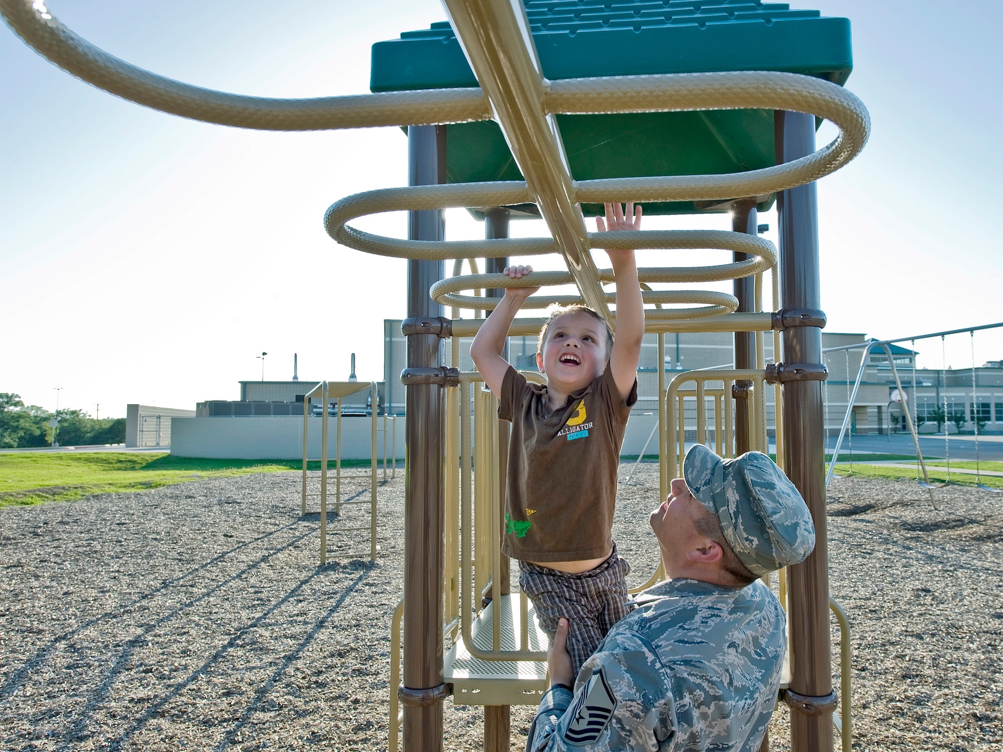 Master Sgt. Rodolfo Gamez helps his son, Tomas, across the monkey bars at their neighborhood park after work. (U.S. Air Force photo/Staff Sgt. Bennie J. Davis III)