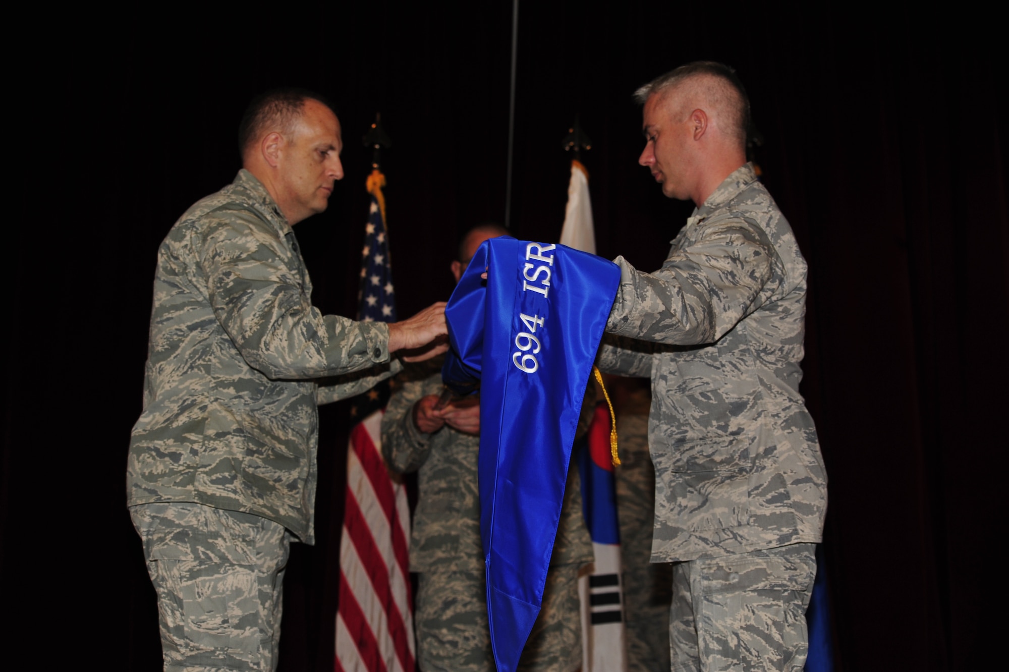 Col. Joseph Dinuovo, commander of the 694th Intelligence, Surveillance and Reconnaissance Group, Osan Air Base, Republic of Korea, and Maj. James Cropper, commander of the newly activated 694th ISS, place the guidon on the staff during an activation ceremony June 4. The 694th ISS is one of three support squadrons recently activated as part of the transformation of Air Force ISR. (U.S. Air Force courtesy photo)