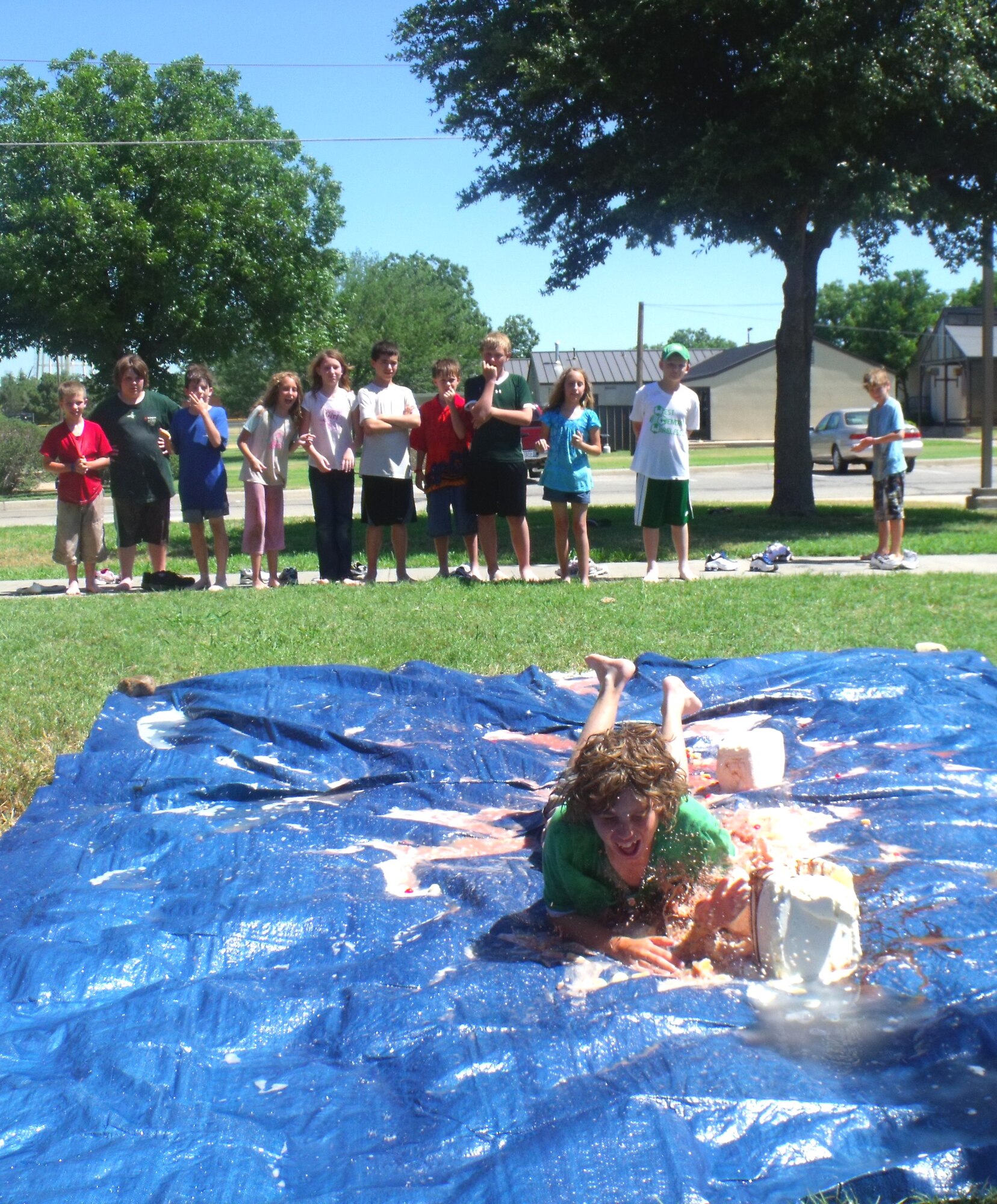 Chase Fraley takes a trip down the Banana Split Slip and Slide June 21 as part of the Youth Center's Wild Week activites. Twelve youths ages 9 and older participated in the week-long event which included activites such as a shaving cream hairdo challenge, fear factor challenges, paintball, body painting and water skiing at the Rec Camp on Lake Nasworthy. (U.S. Air Force photo/Omar Matos)