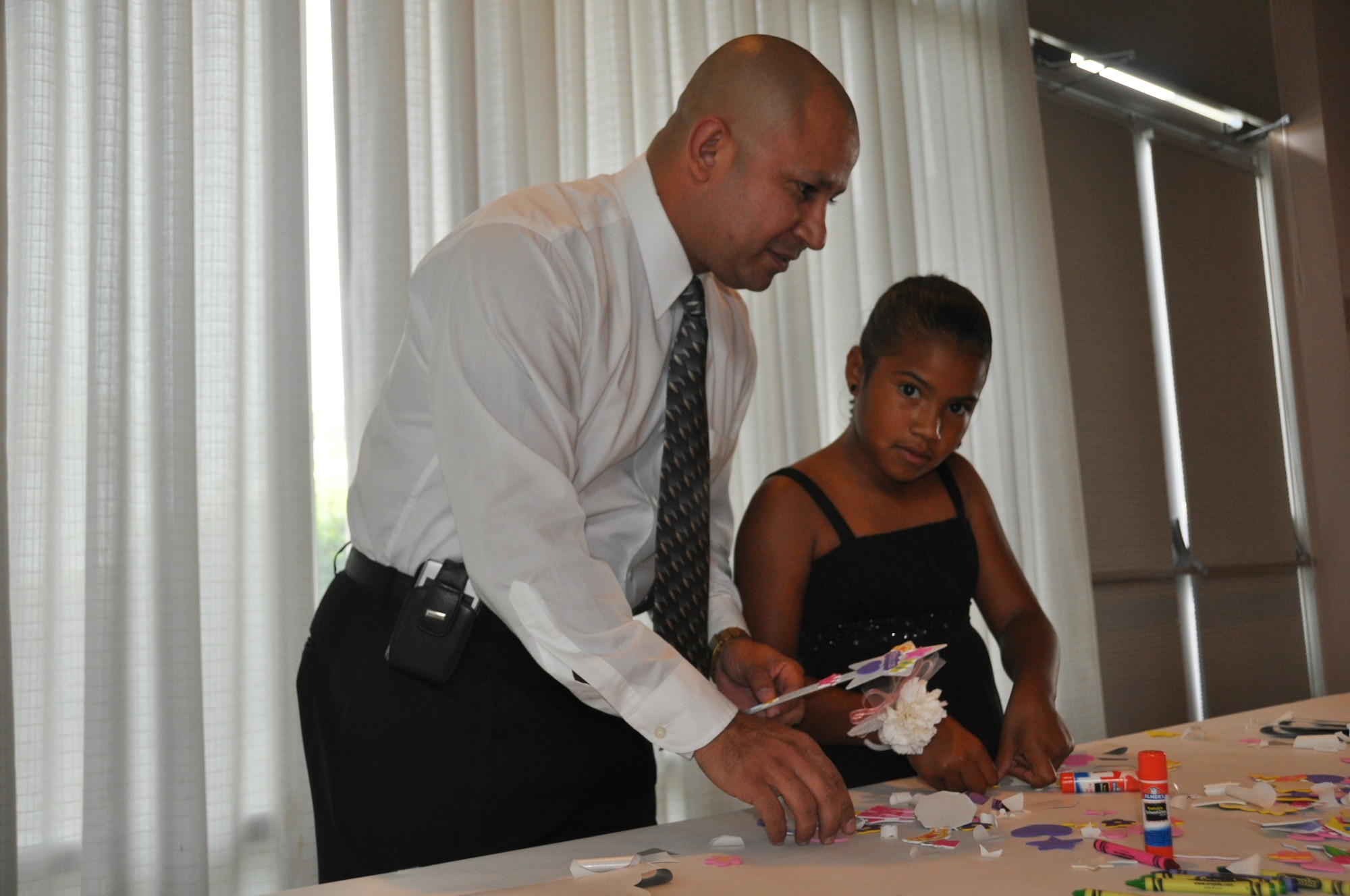 Senior Master Sgt. Paul Figueroa, 325th Communications Squadron Cyber Operations superintendent, joins his eight-year-old daughter Kieria Figueroa, in making a tiara during the Daddy Daughter Dance June 17.  (U.S.  Air Force photo /Senior Airman Veronica McMahon)