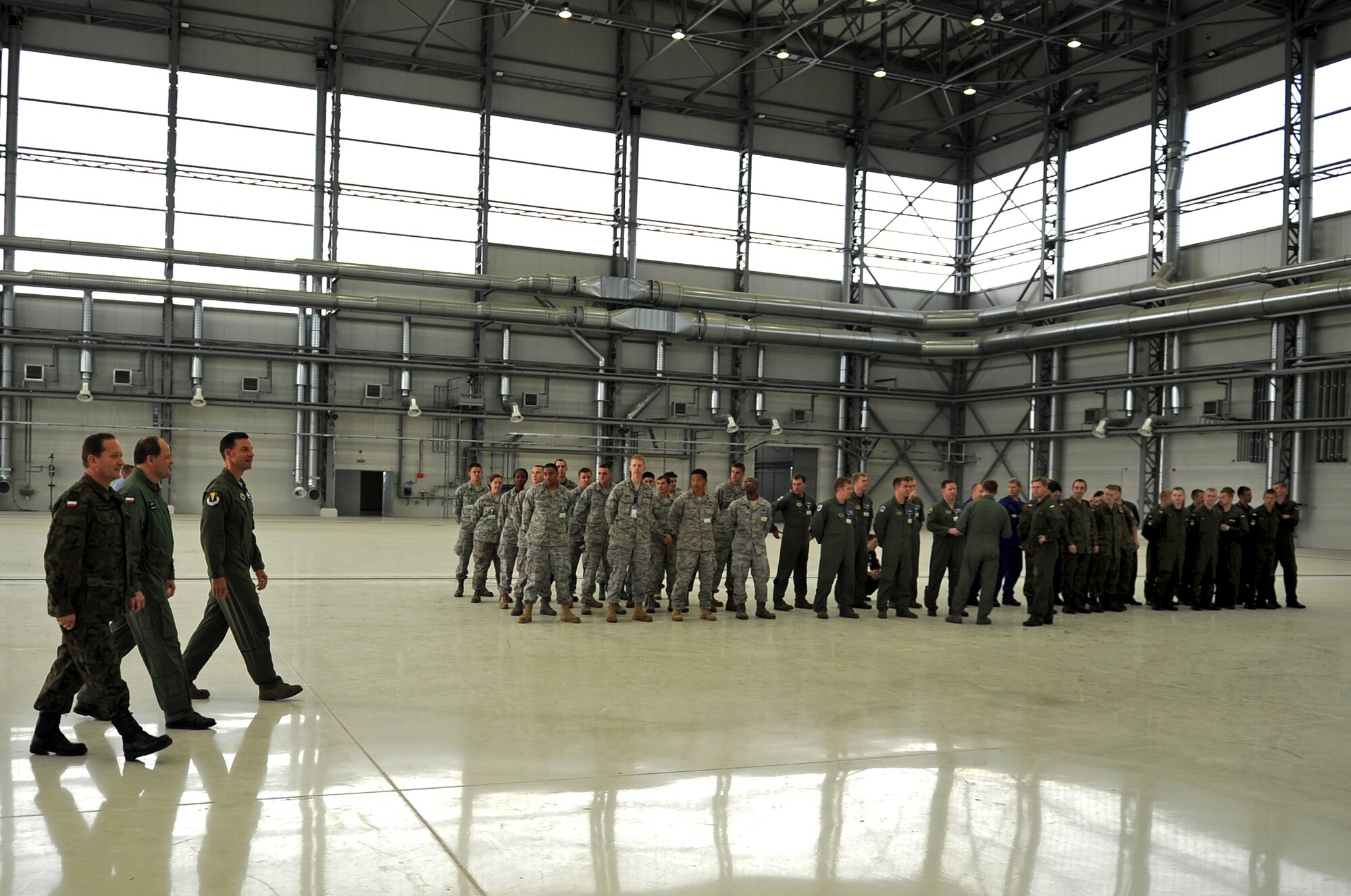 Poland Air Force Brig. Gen. Tadeusz Mikutel, 3rd Airlift Wing commander, Lt. Col. Andrew Gornicki, 3rd Airlift Wing deputy commander, and U.S. Air Force Brig. Gen. Mark Dillon, 86th Airlift Wing commander, enter a remodeled hangar to speak to U.S. and Polish Airmen during a ceremony on Powidz Air Base, Poland, June 21, 2010. The purpose General Dillon's visit to Poland was to sign a letter of intention representing the 86th AW and the 3rd Airlift Wing as 'sister wings' and to build partnership with our new 'sister wing'. (U.S. Air Force photo by Airman 1st Class Grovert Fuentes-Contreras)(Released)