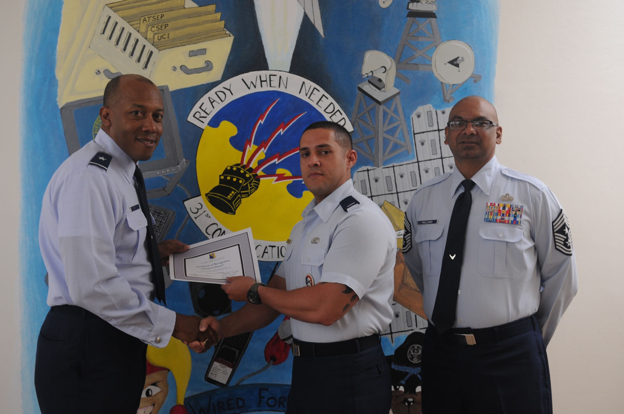 Brig. Gen. C.Q. Brown Jr., 31st Fighter Wing commander, congratulates 1st Lt. Axel Zengotita , 31st Communications Squadron,on his selection as one of Aviano's Finest as Chief Master Sgt. Laten Williams, 31st FW command chief, looks on. (U.S. Air Force photo/ Staff Sgt. Nadine Y. Barclay)
