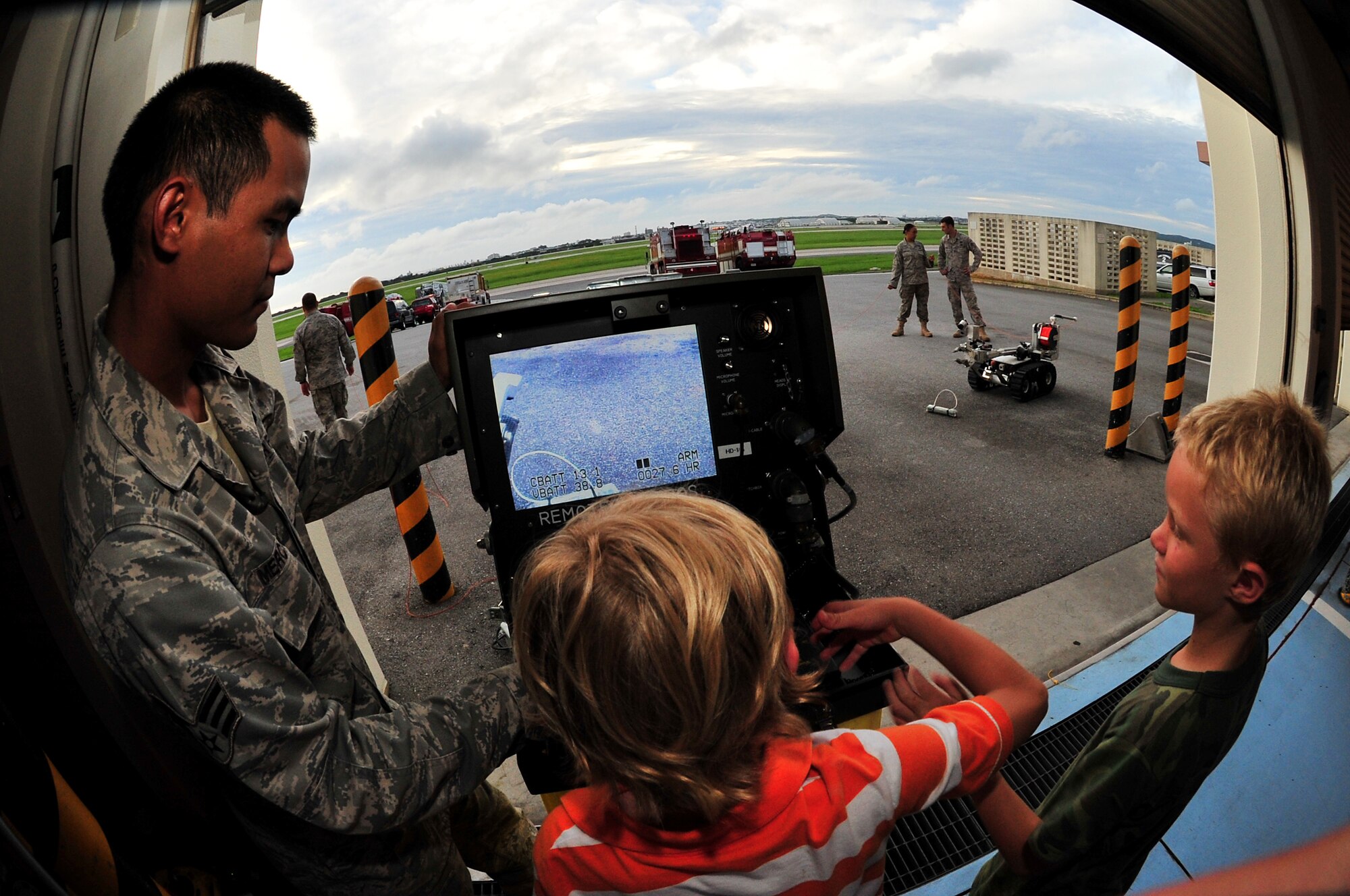 Senior Airman Jesse Mercado demonstrates the use of a mechanical robot to Aiden Sutton, age 8, and his brother Elijah, age 9, during the Deployed Spouses Dinner held at the Fire Department Headquarters, June 19. More than 90 spouses and 58 children attended the dinner hosted by the 18th Civil Engineer Group.   (U.S. Air Force photo/Tech. Sgt. Rey Ramon)     