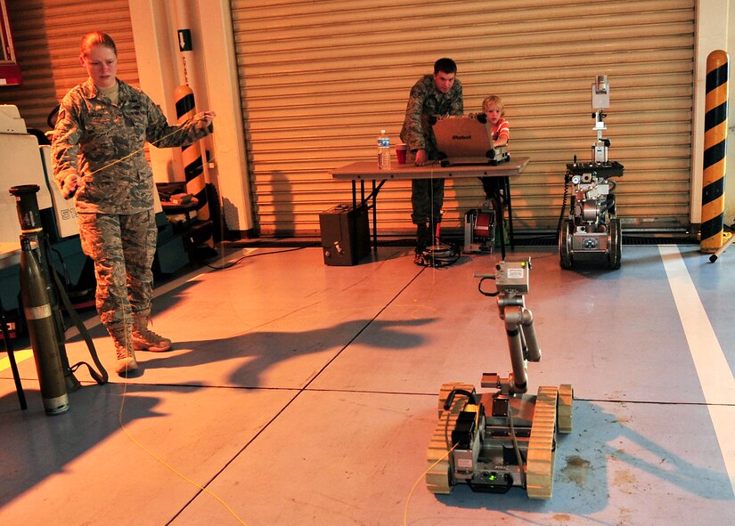 Staff Sgt. Molly Callen and Senior Airman David Dezwaan demonstrate the use of an F6A robot to Aiden Sutton, age 8, during the Deployed Spouses Dinner held at the Fire Department Headquarters, June 19. More than 90 spouses and 58 children attended the dinner hosted by the 18th Civil Engineer Group.   (U.S. Air Force photo/Tech. Sgt. Rey Ramon)  