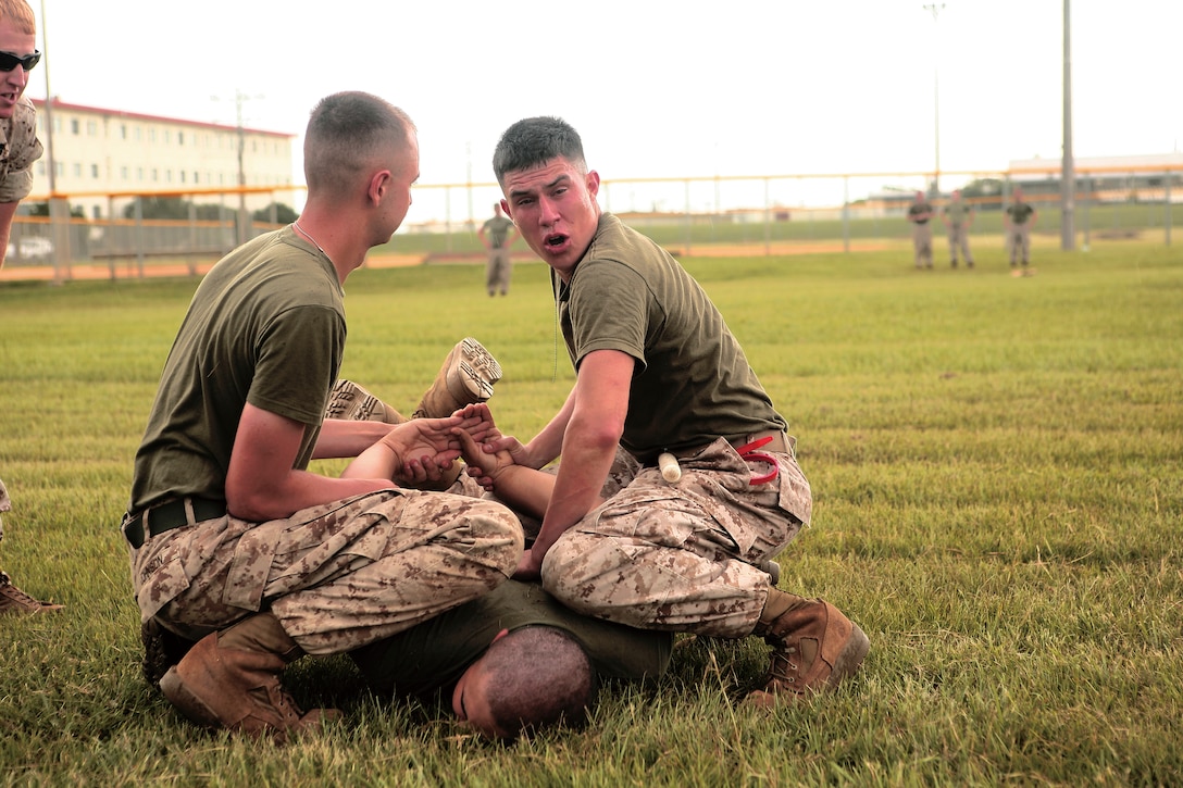 Lance Cpl. Terry Martin, a maintenance management specialist with 3rd Intelligence Battalion, III Marine Expeditionary Force, subdues a mock attacker with the help of Lance Cpl. Joshua Johnson, a special intelligence systems administrator and communicator, 3rd Intel. Bn., during an Oleoresin Capsicum Level-1 contamination course on Camp Hansen, June 23.
