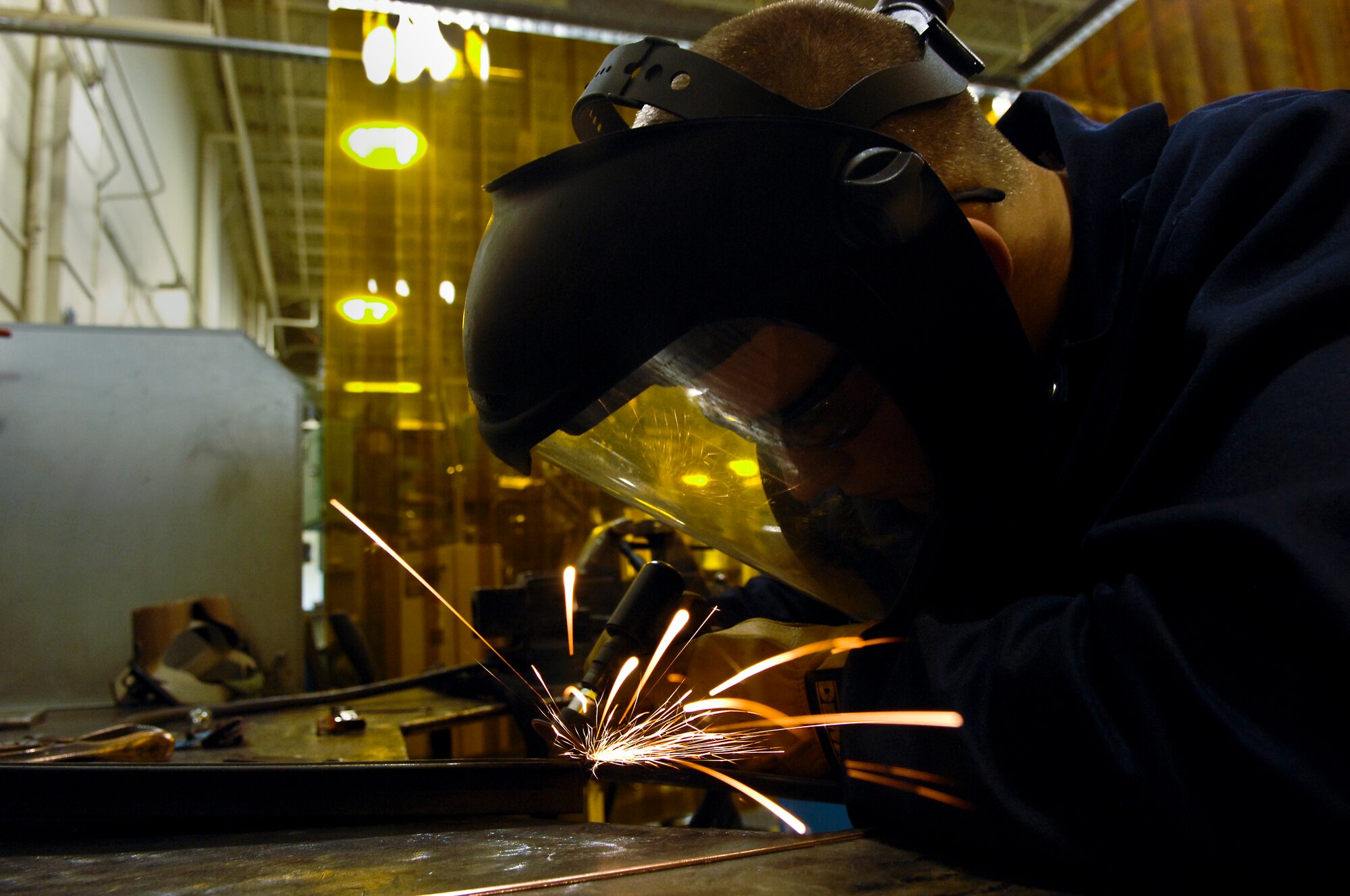 Sparks fly as Airman 1st Class Derek Johnson, 3rd Equipment Maintenance Squadron, grinds down a weld on a piece of air-ground equipment, June 22. The Metals Technologies shop is responsible for many repair and maintenance jobs on Elmendorf. (Air Force photo by Airman 1st Class Jack Sanders)