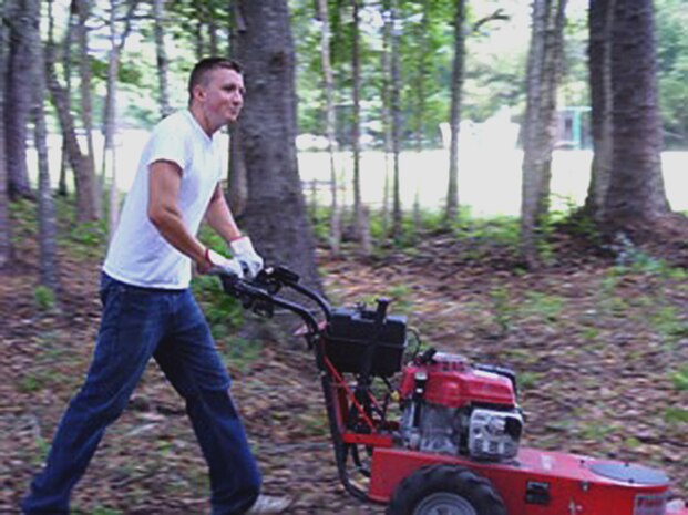 Senior Airman Shawn Goggin pushes a high-wheel trimmer during a volunteer event at Windwood Farm in Awendaw, S.C., June 19, 2010. Airman Goggin and members of Airmen Against Drunk Driving helped the organization meet their mission by painting classrooms, trimming and weeding around the houses and buildings on the farm?s 110 acre plot of land, cleaning the houses the children work, play and live in, and clearing undergrowth around their baseball field. Airman Goggin is with the 14th Airlift Squadron. (Courtesy photo)