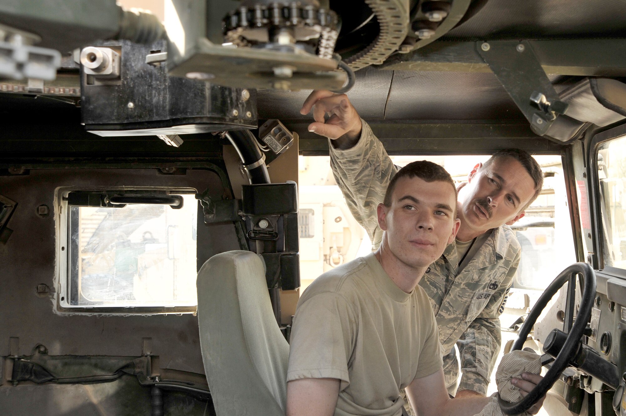 Senior Master Sgt. CJ Slifko and his son, Airman 1st Class Ryan Slifko, inspect the turret chain on a Humvee June 19, 2010, at Sather Air Base, Iraq. Sergeant Slifko is the vehicle fleet manager for the 447th Expeditionary Logistics Readiness Squadron. Airman Slifko is a vehicle mechanic with the 447th ELRS. (U.S. Air Force photo/Senior Airman Perry Aston)