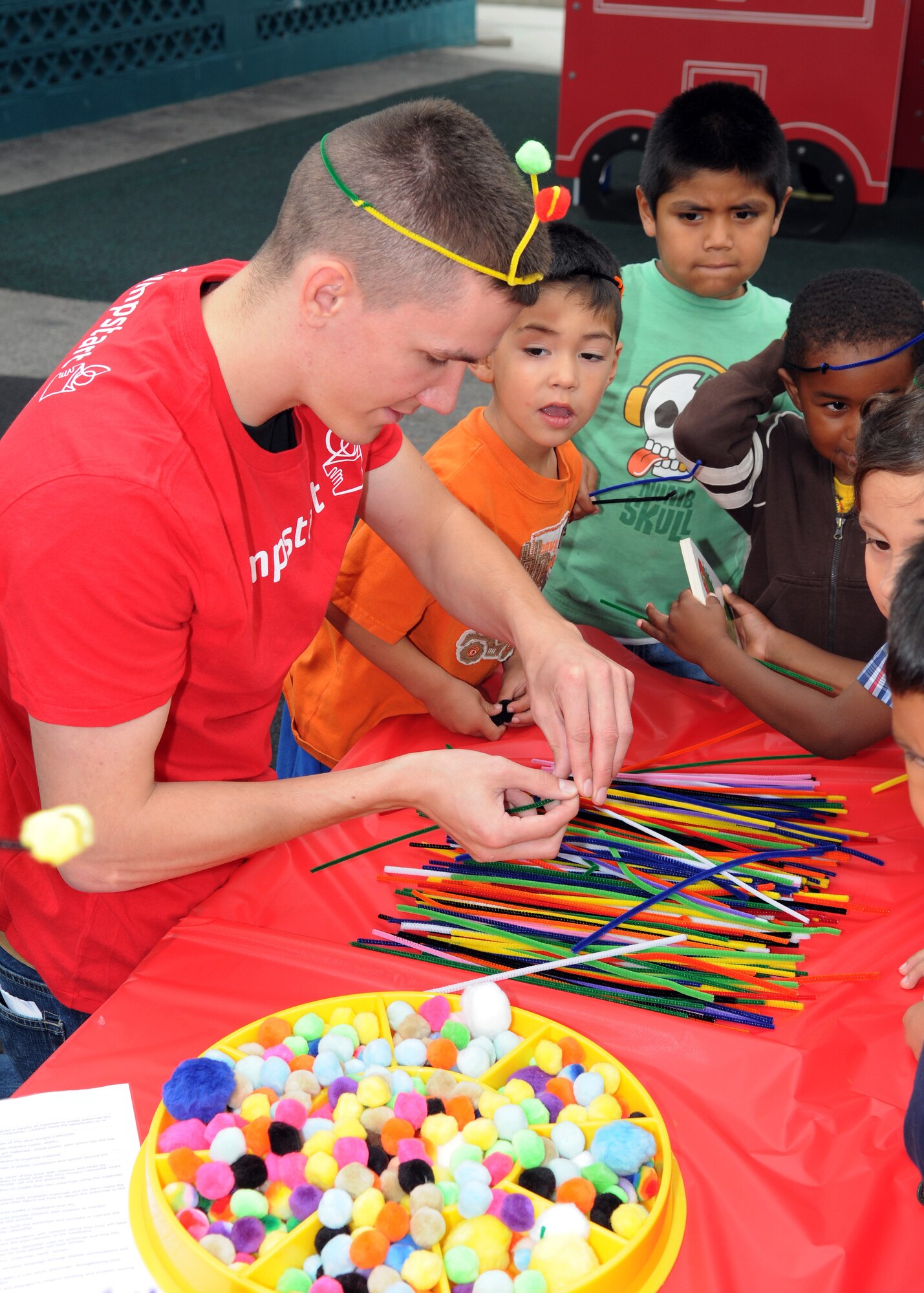 A volunteer from the 61st Communications Squadron helps children at the Inglewood Child Development Center make antenna out of pipe cleaners, June 22.  (Photo by Jim Gordon)