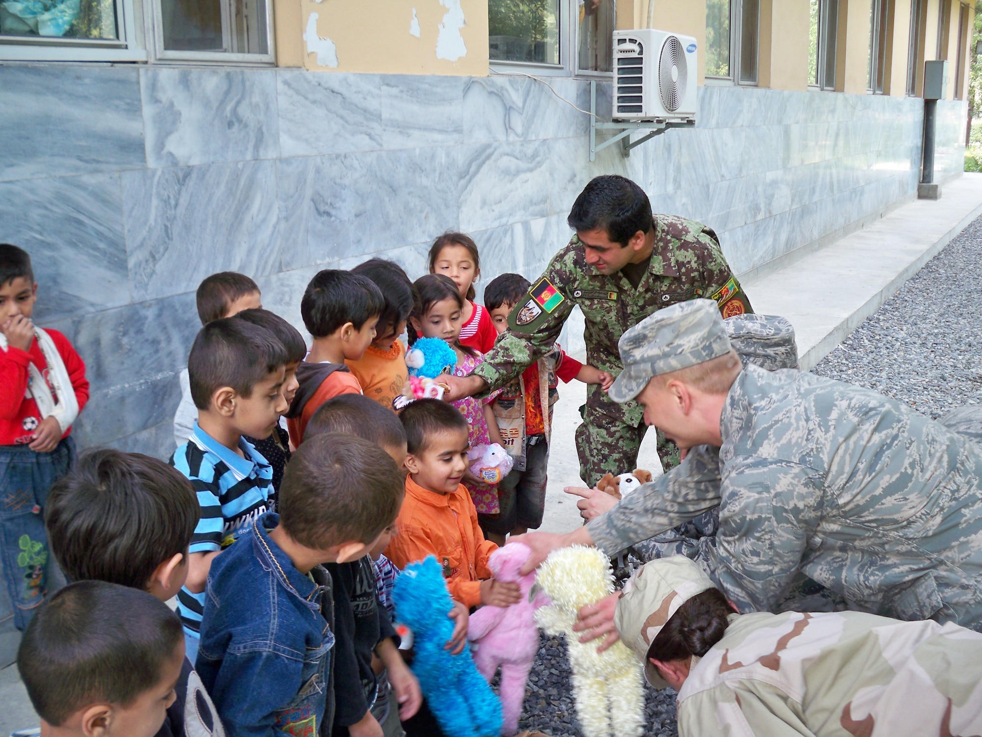 SOUTHWEST ASIA -- Deployed Airmen from Buckley Air Force Base, Colo., as well as other members of the NATO task force in Afghanistan, pass out plush animals to Afghan orphans. In addition to the 70 teddy bears, Buckley volunteers collected clothes, shoes, food and toys for the orphans.  (U.S. Air Force photo)