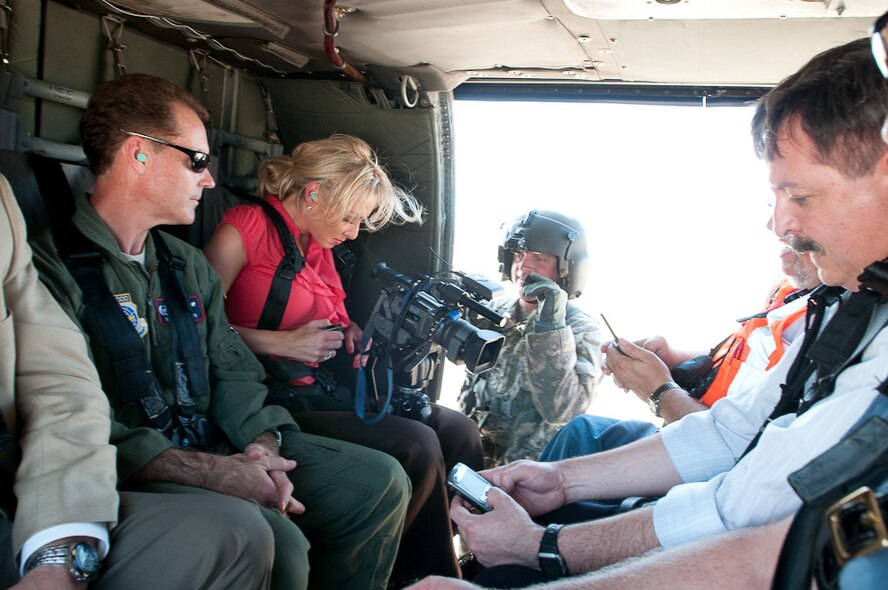 Colonel Mike McEnulty (left), 139th Airlift Wing Commander, looks on as a Mo. National Guard blackhawk crew member straps in local St. Joseph, Mo. journalists for a flight to Northern Missouri to survey recent flooding, June 22, 2010. The flight was generated to provide Mo. Governor Jay Nixon and Brigadier General Stephen Danner, Mo. Adjutant General, a closer look at recent developments.  (U.S. Air Force photo by Master Sgt. Shannon Bond/Released)