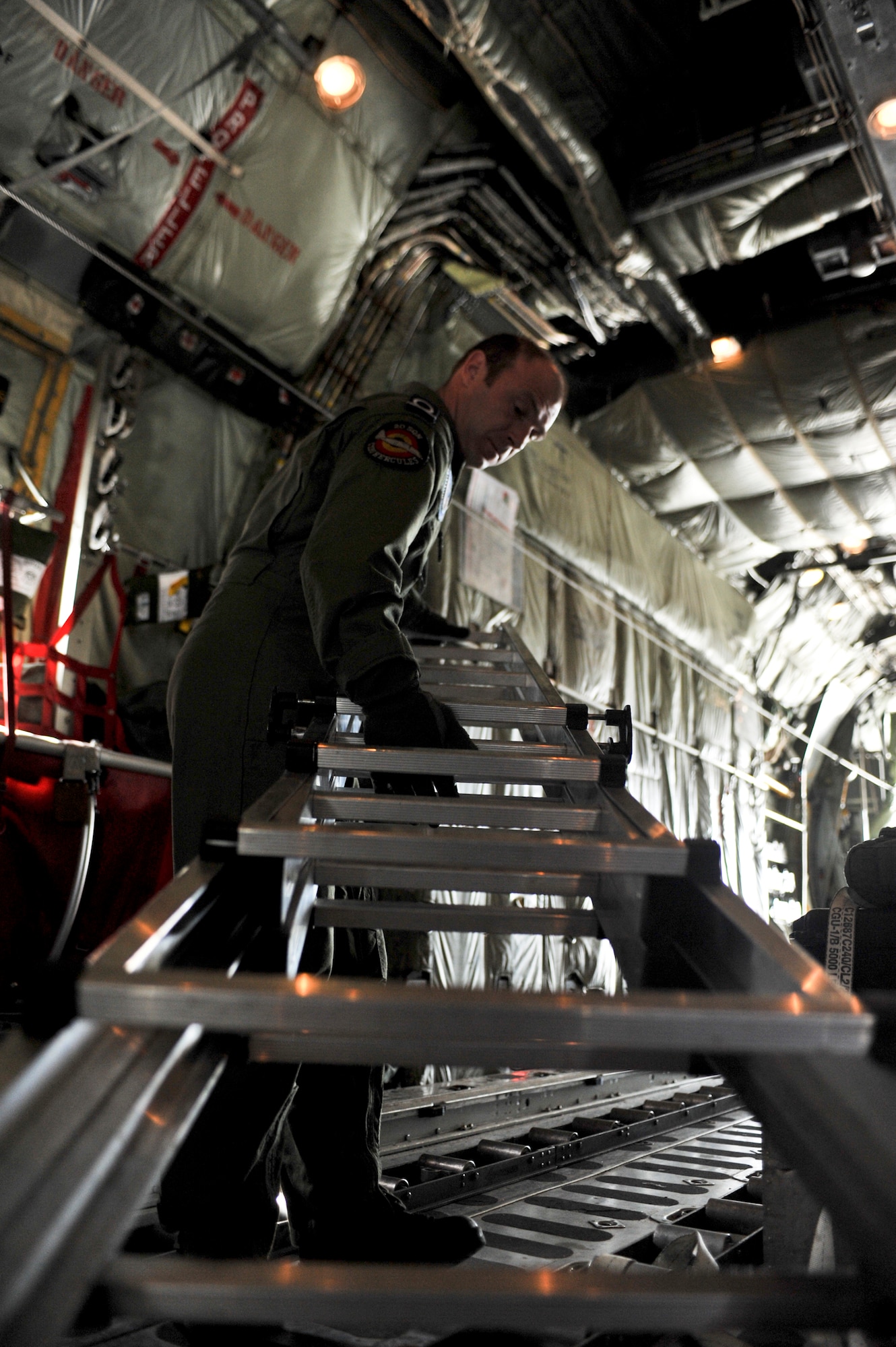 JOINT BASE ELMENDORF-RICHARDSON, Alaska – Adjudant Gert Van Den Berghe, Belgian Air Component 15th Air Transport Wing 20th Squadron loadmaster, moves a ladder before a Belgian C-130 Hercules takes off June 22. This was the first time the BAC has participated in RF-Alaska. (Air Force photo by Airman 1st Class Christopher Gross)