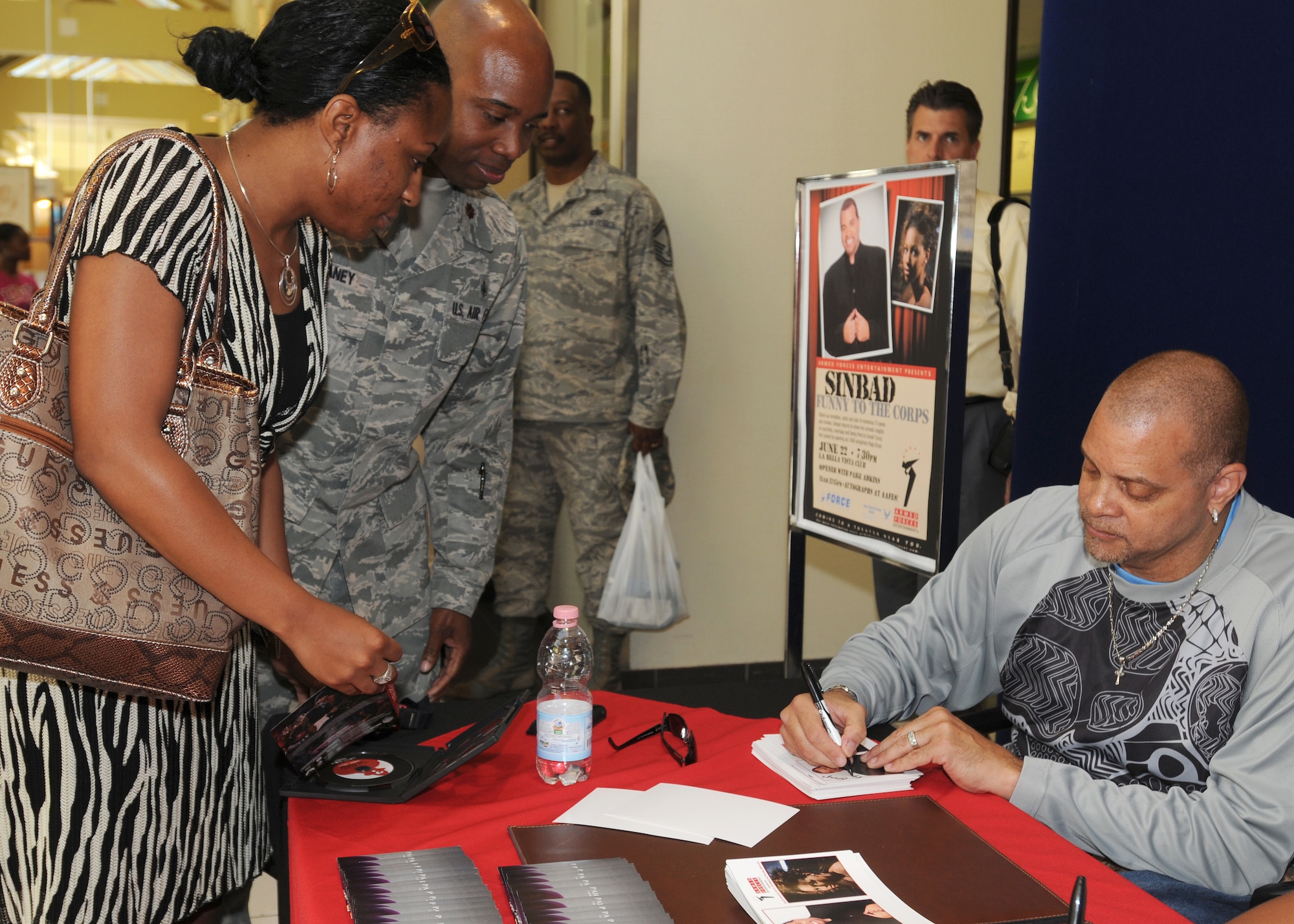 Actor and comedian Sinbad signs autographs for Maj. George Delaney, 31st Medical Group practice manager, and his wife, Tonja, June 22 at the Base Exchange.  Sinbad?s ?Funny to the Corps? tour with rhythm and blues artist Paige Bryan kicked off June 10 in the United Kingdom.  (U.S. Air Force photo/Senior Airman Tabitha M. Mans)