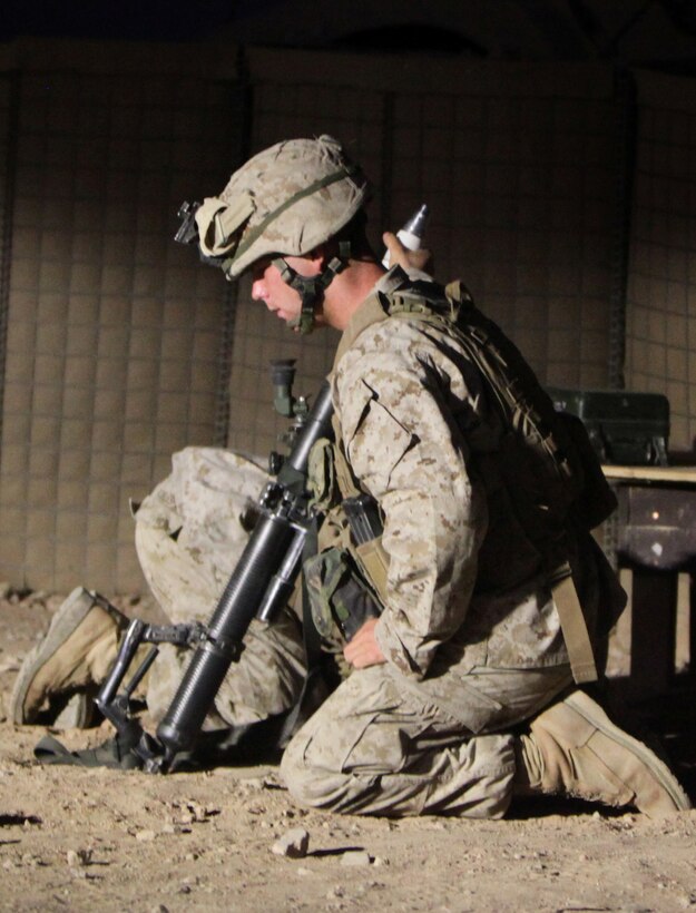 Corporal Ryan Thayer, a squad leader for 2nd Platoon, Alpha Company, 1st Battalion, 2nd Marine Regiment, Regimental Combat Team 2, prepares to drop an illumination round into the M224 60 mm light weight mortar tube as Cpl. Jonathan Roblespaul, a mortarman section leader with Alpha Co., ducks into a safe position at Combat Outpost Cafferetta, June 26.::r::::n::Mortars aren’t just effective when it means pushing the enemy from their positions during a fight. “We often fire illumination rounds just to show our presence, to let the enemy know that we are still here and have some muscle with us,” said Thayer.::r::::n::