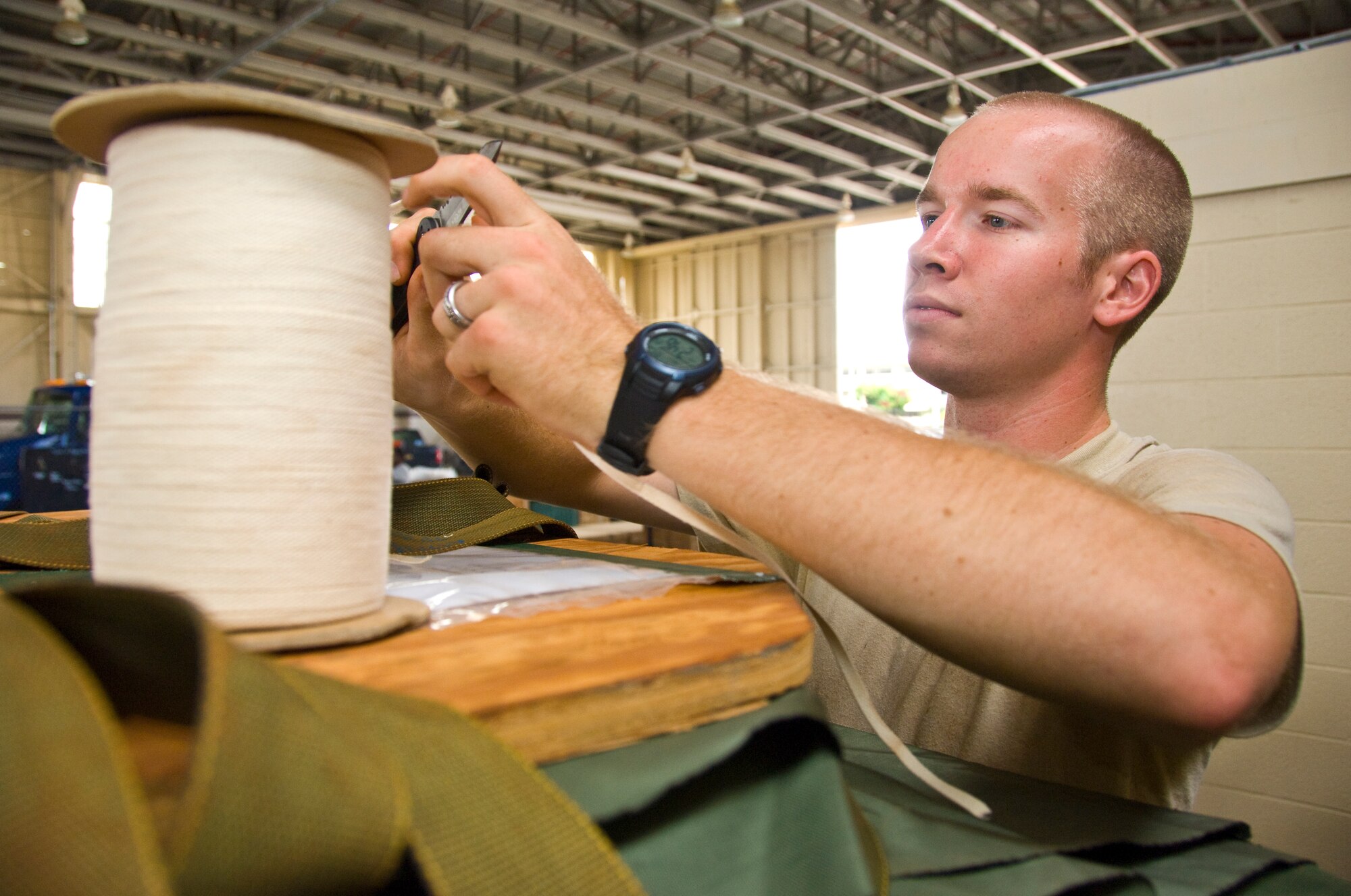 Senior Airman Lindsey McCoy, 647th Logistics Readiness Squadron air transportation specialist, removes a piece of cord from its spool at Hangar 7 June 18. The cardboard was used in a pallet built to deliver  food through airdrop to Marines and Seabees on the island of Hawaii as part of the Rim of the Pacific exercise. (U.S. Air Force photo by Staff Sgt. Nathan Allen)