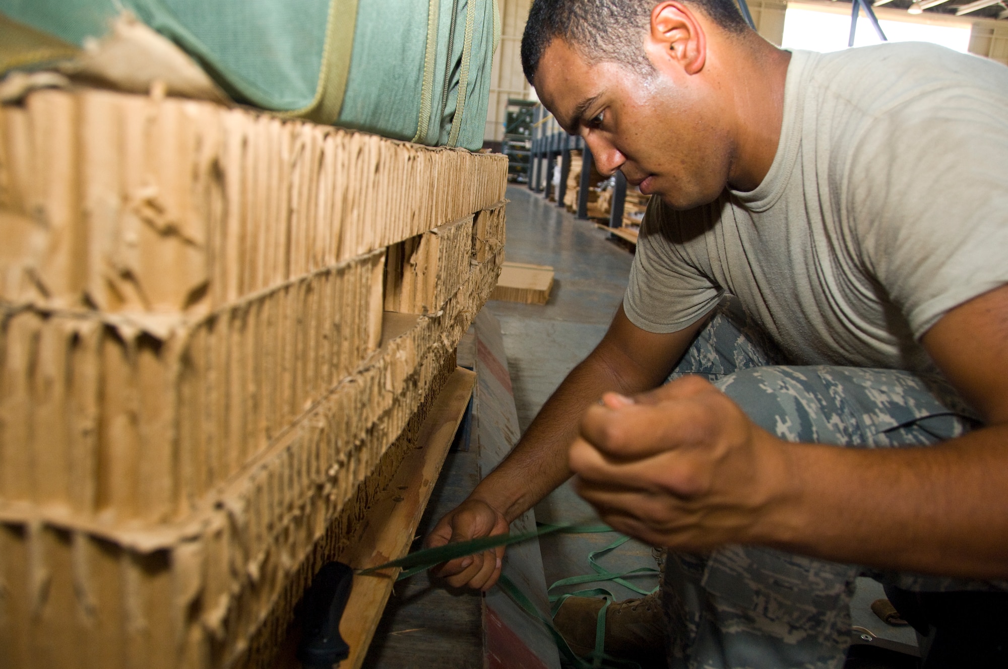 Staff Sgt. Shannon Lee, 647th Logistics Readiness Squadron air transportation specialist, secures the base of a pallet with cord at Hangar 7 June 18. The cardboard was used in a pallet built to deliver  food through airdrop to Marines and Seabees on the island of Hawaii as part of the Rim of the Pacific exercise. (U.S. Air Force photo by Staff Sgt. Nathan Allen)