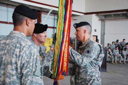 SOTO CANO AIR BASE, Republic of Honduras -- Col. Gregory Reilly, the Joint Task Force-Bravo commander, passes the guidon to Lt. Col. James Kanicki during a change of command ceremony here June 24. In accepting the colors symbolizing the 1st Battalion, 228th Aviation regiment, Colonel Kanicki took command of the unit from Lt. Col. Salome Herrera Jr. (left).  (U.S. Air Force photo/Tech. Sgt. Benjamin Rojek)