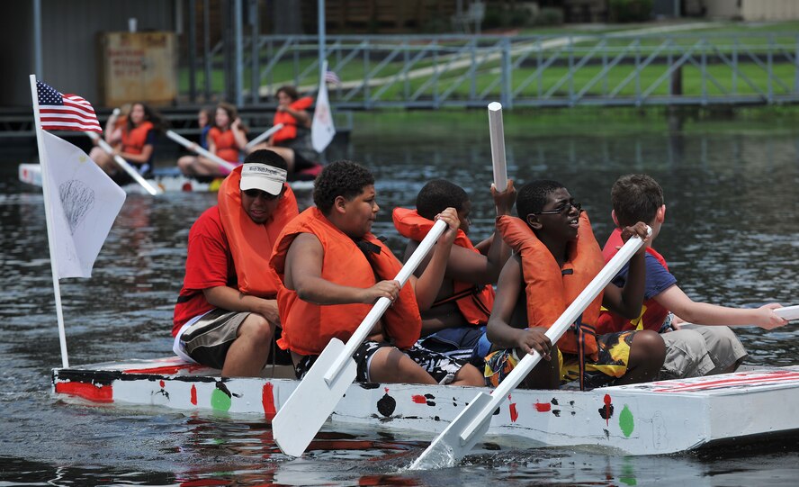 MOODY AIR FORCE BASE, Ga. -- A chaperone and youth use paddles to steer a self-made sailboat at Grassy Pond in Valdosta, Ga., June 18. Twenty-four summer camp youth between nine to 12 years old worked for a week to build three large wooden sailboats, funded by a grant received from Air Combat Command. (U.S. Air Force photo by Airman 1st Class Joshua Green/RELEASED)