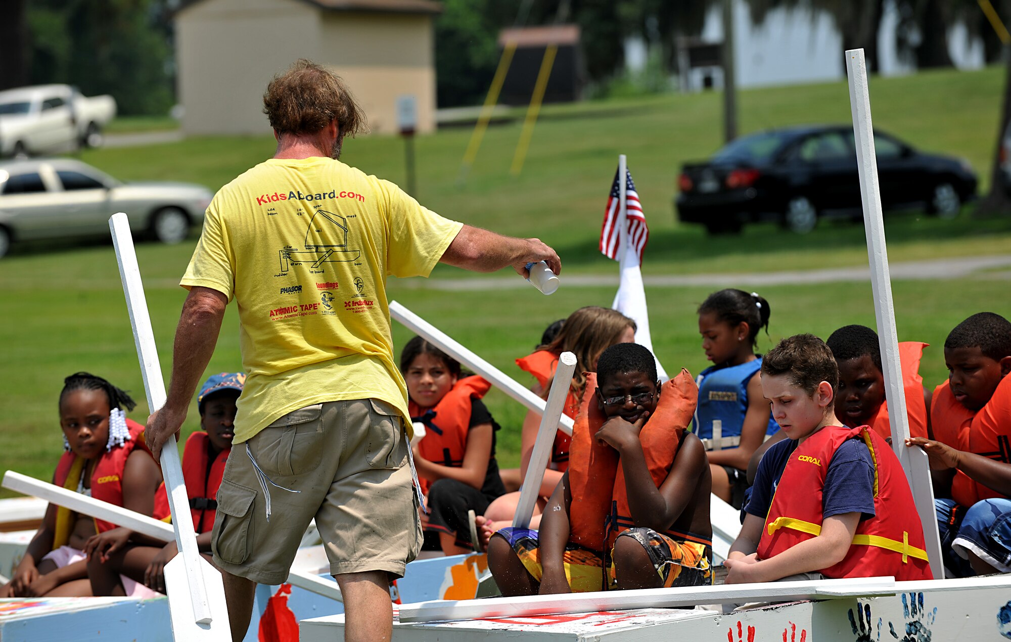 MOODY AIR FORCE BASE, Ga. -- Curtis Tucker, Kids Aboard Workshop certified educator, pours water on to the front of the sailboats as a sign of good luck before letting the youth enter the water during the Youth Center Boat Launching event at Grassy Pond in Valdosta, Ga., June 18. Mr. Tucker has run the program for about seven years and uses the program to teach kids how to utilize and apply skills to work as a team through boat building. (U.S. Air Force photo by Airman 1st Class Joshua Green/RELEASED)