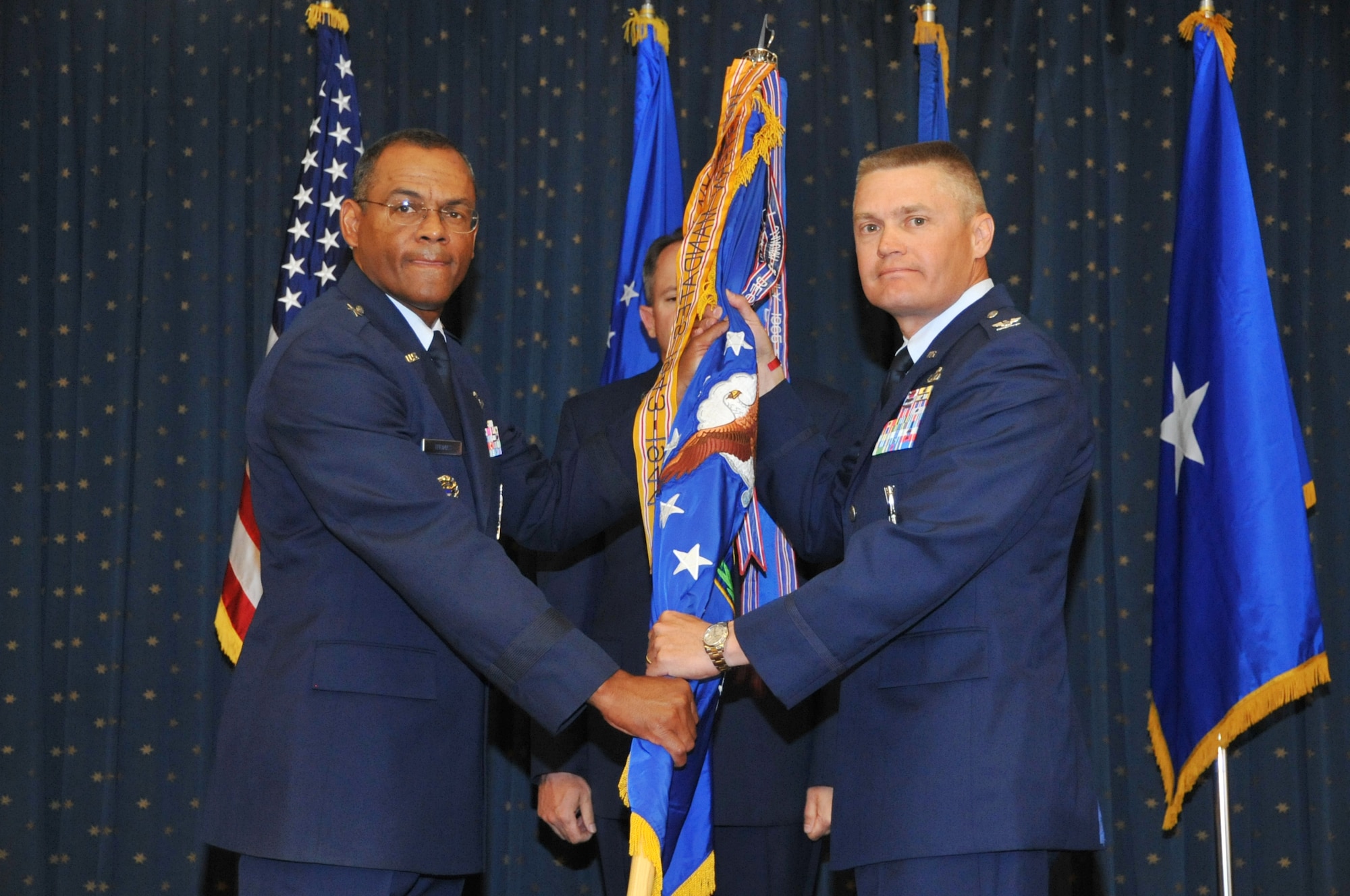 Left, Brig. Gen. Everett Thomas, Air Force Nuclear Weapons Center commander, passes the 498th Nuclear Systems Wing guidon to Col. Walter Lindsley during a change-of-command ceremony June 21. USAF Photo by Elizabeth Martinez