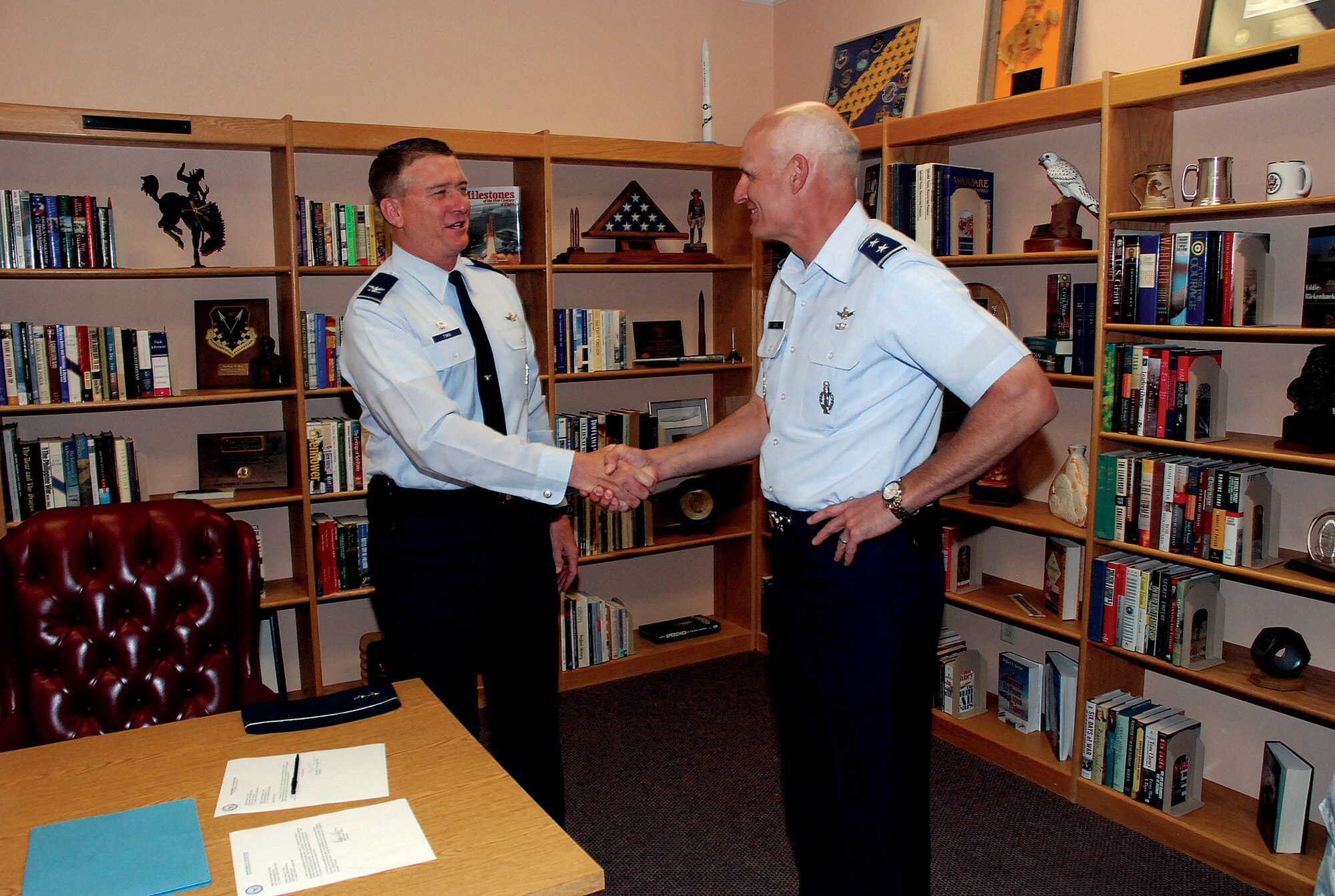 Col. Greg Tims, 90th Missile Wing commander, shakes the hand of Maj. Gen. Roger W. Burg, Twentieth Air Force commander, in the base library after General Burg signed over his professional library to Warren on Monday. (Photo by Airman 1st Class Jennifer Viveiros)