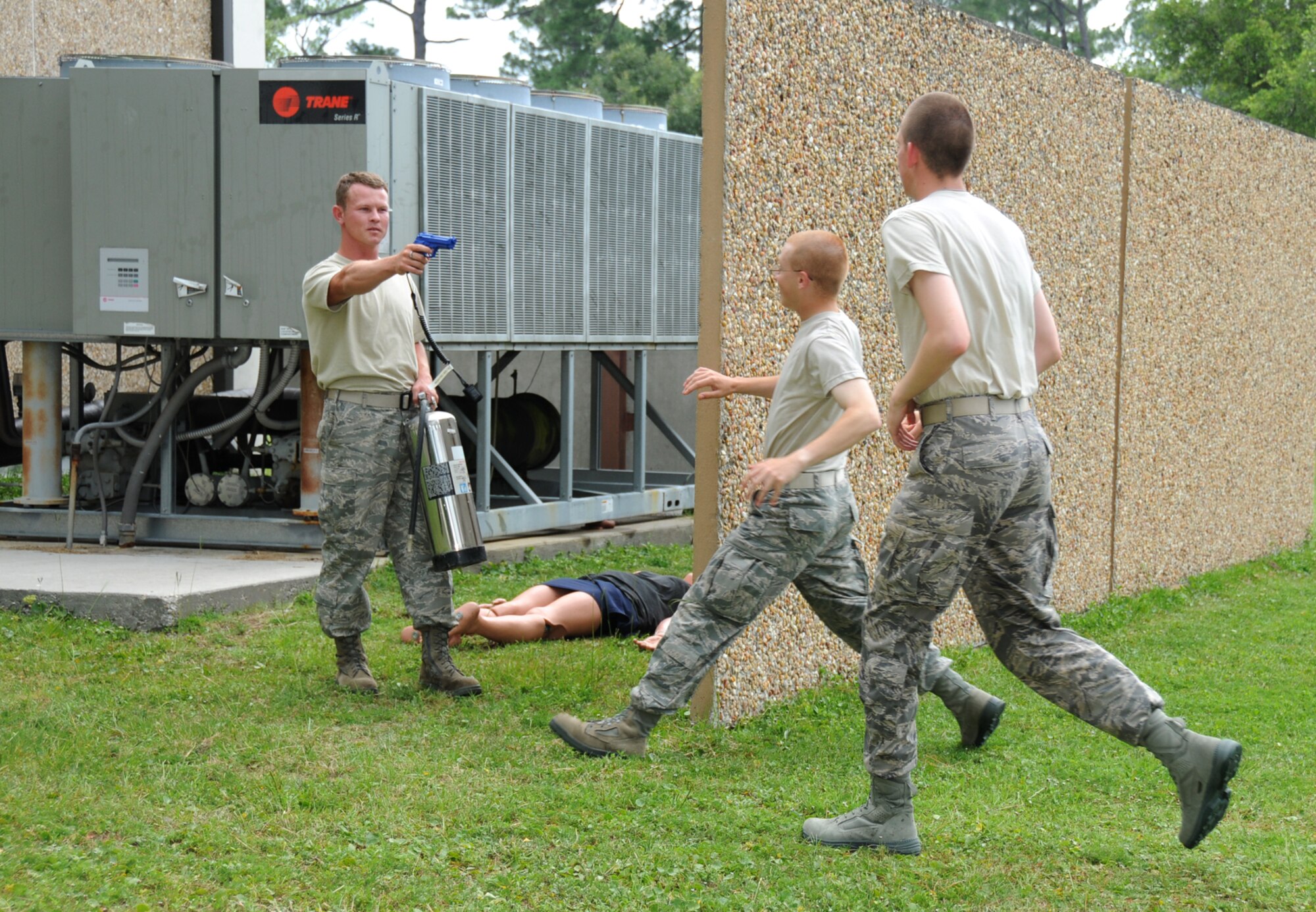 Staff Sgt. Blaine Hunter, 81st Logistics Readiness Squadron, portrays a terrorist aiming a gun at Airmen Basic Nicholas Alexander and Zachariah Westerfield who try to apprehend him during a June 15 exercise. Airmen Alexander and Westerfield are 336th Training Squadron students.  In the scenario, Sergeant Hunter sprayed ricin, a toxin used in chemical warfare, into the air conditioning system at Blake Fitness Center.  (U.S. Air Force photo by Kemberly Groue)
