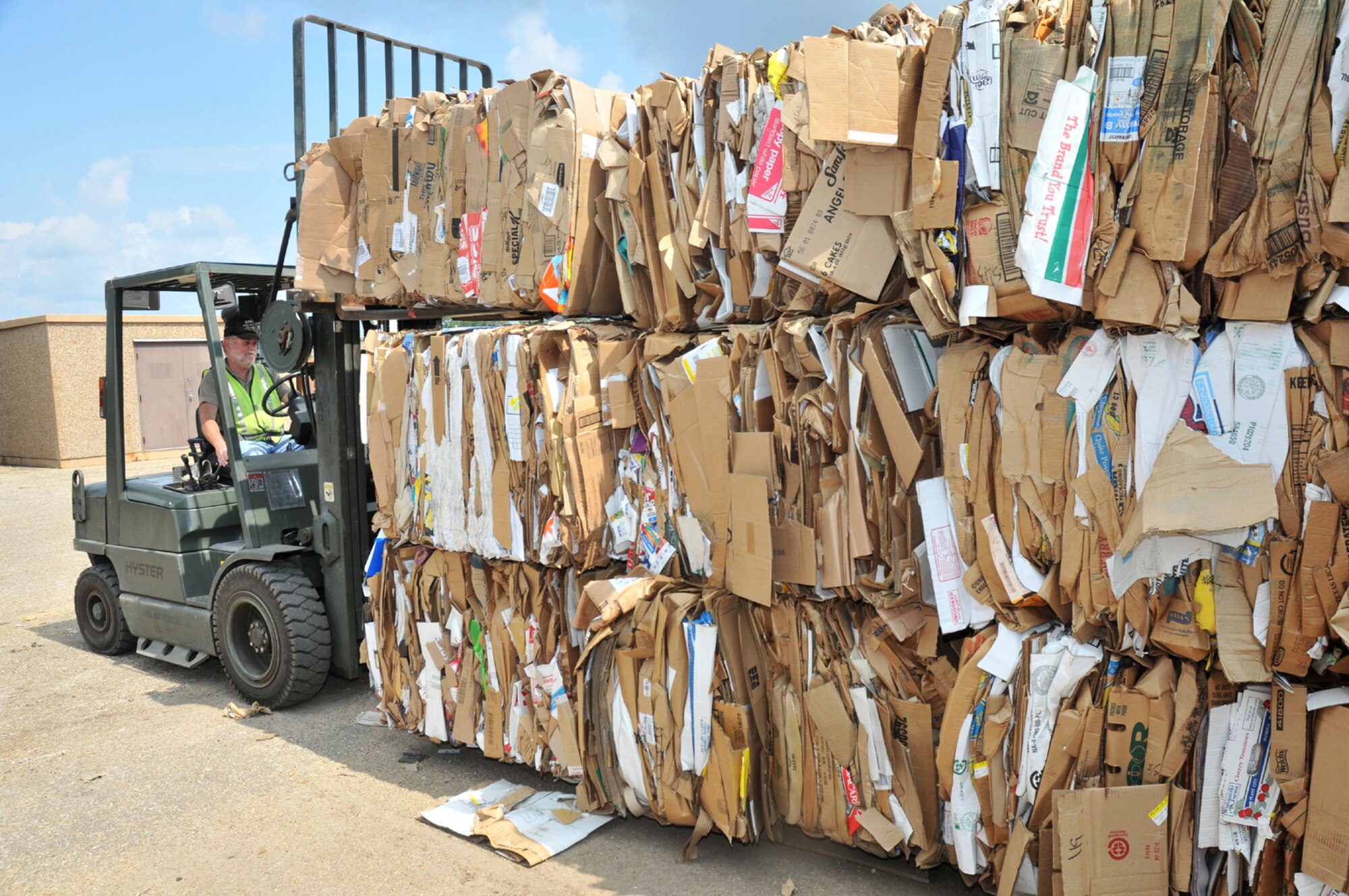 Recycling center director Robert Marks maneuvers a towering stack of cardboard bales to a staging area behind the recycling center.   (U.S. Air Force photo by Adam Bond)
