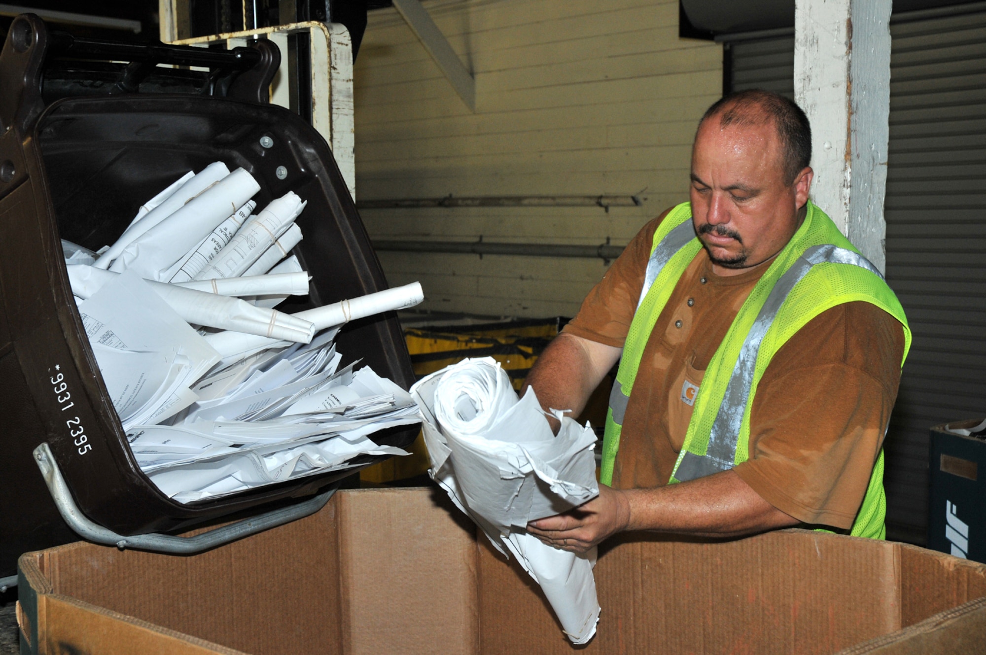 Billy McCasland prepares paper collected from recycling bins located throughout the base for processing. The recycling center generates revenue by selling processed material to local paper mills.  (U.S. Air Force photo by Adam Bond)